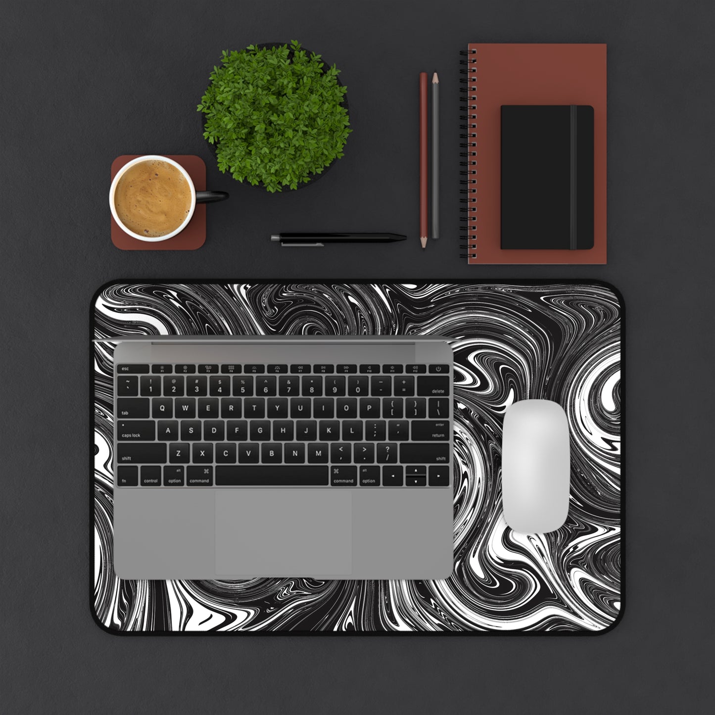 A 12" x 18" desk mat with black and white swirls. A laptop and mouse sit on top of it.