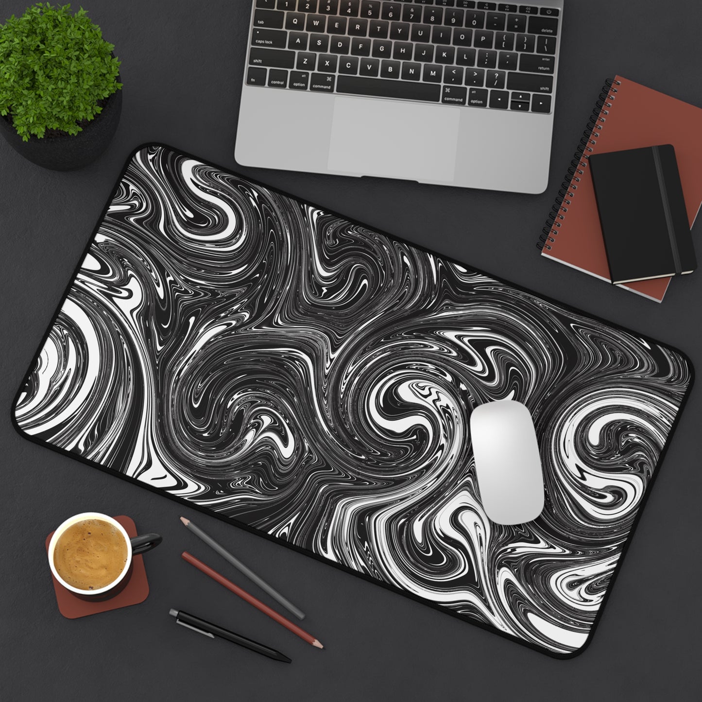 A 12" x 22" desk mat with black and white swirls sitting at an angle.