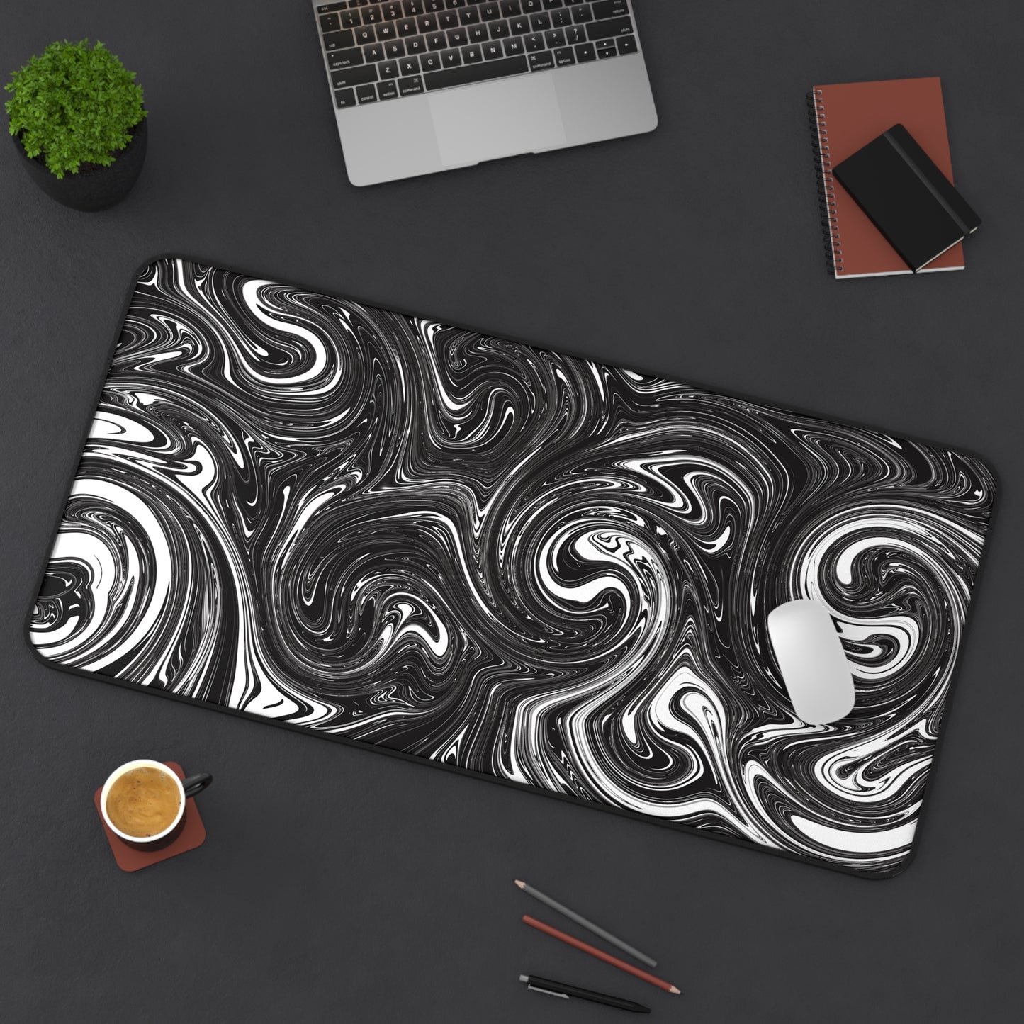 A 31" x 15.5" desk mat with black and white swirls sitting at an angle.