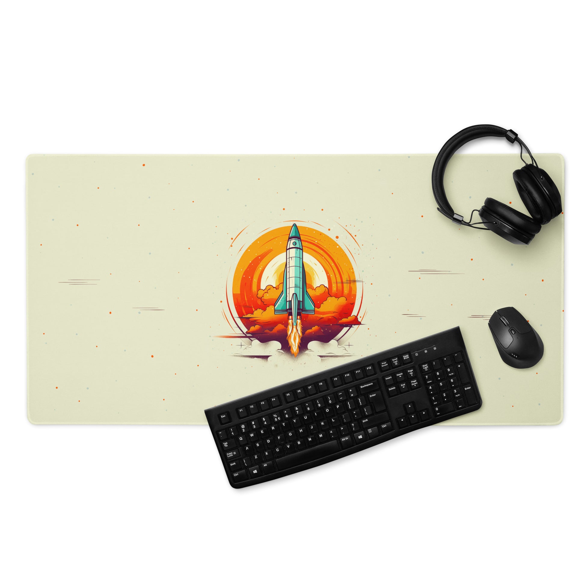 A 36" x 18" desk pad with a space shuttle blasting off. With a keyboard, mouse, and headphones sitting on it. Beige in color.