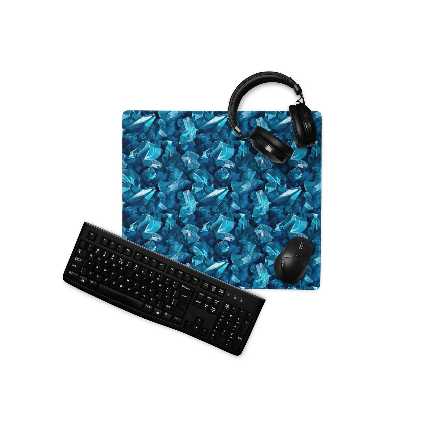 An 18" x 16" gaming desk pad with blue crystals. A keyboard, mouse, and headphones sit on it.