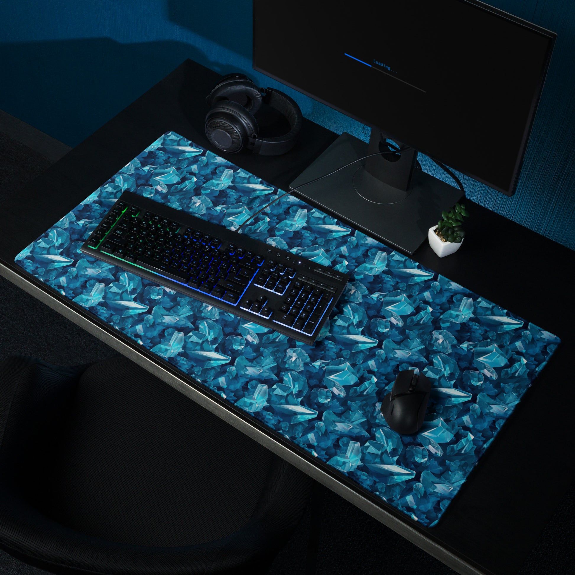 A 36" x 18" gaming desk pad with blue crystals. It sits on a black desk with a monitor, keyboard, and mouse.