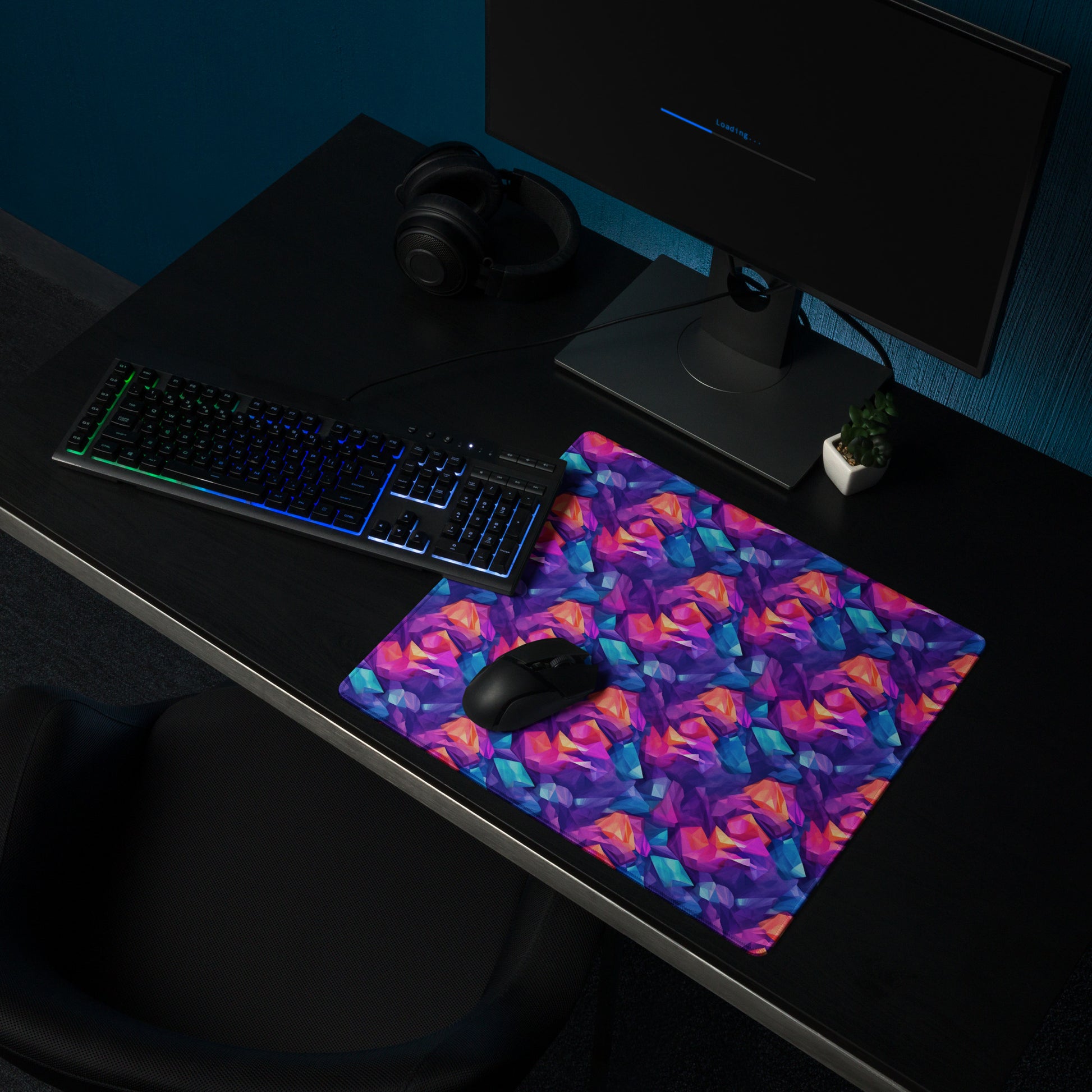 An 18" x 16" gaming desk pad with blue, purple, and orange crystals. A keyboard and mouse sit on it.
