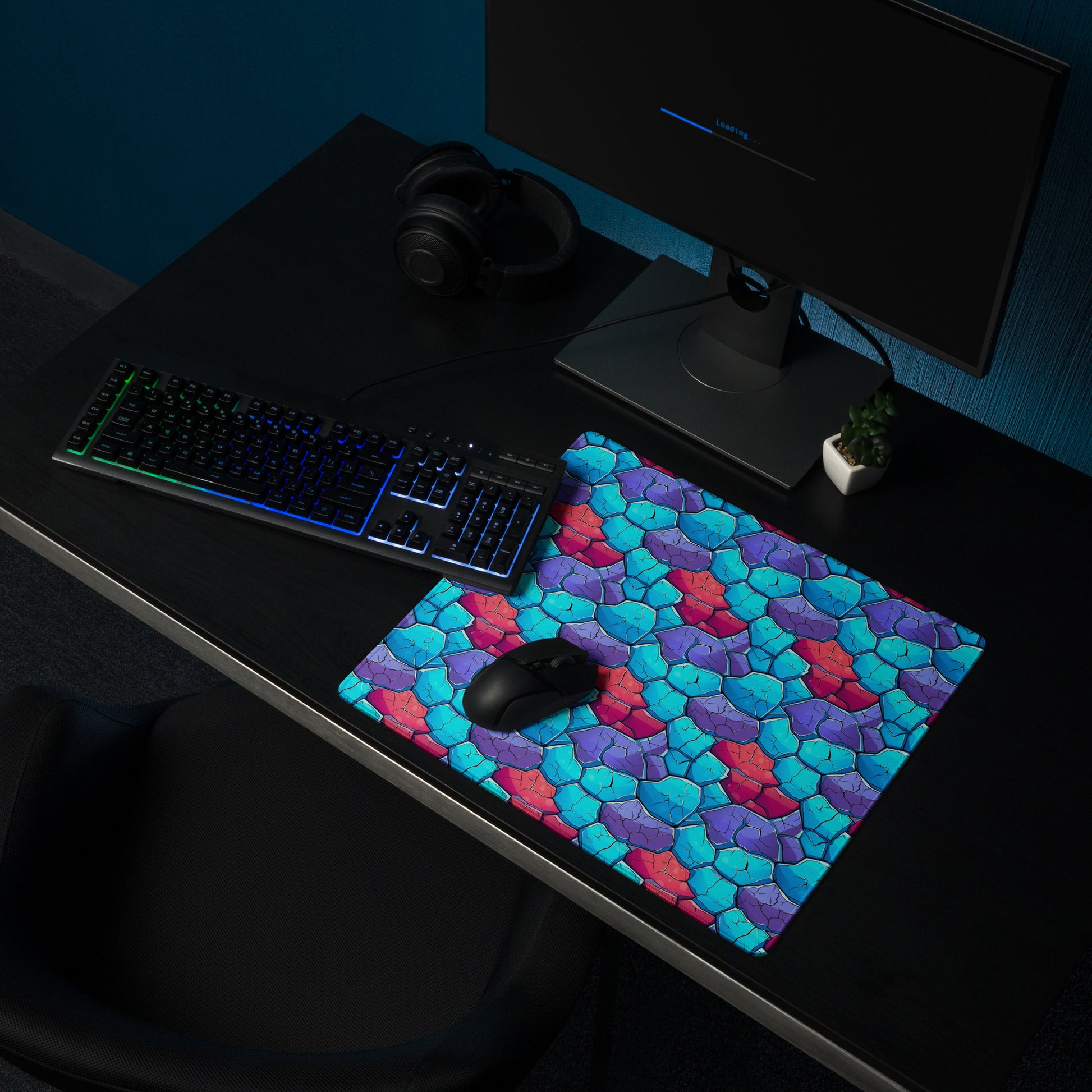 An 18" x 16" gaming desk pad with blue, red, and purple crystals. It sits on a black desk with a keyboard, monitor, and mouse.