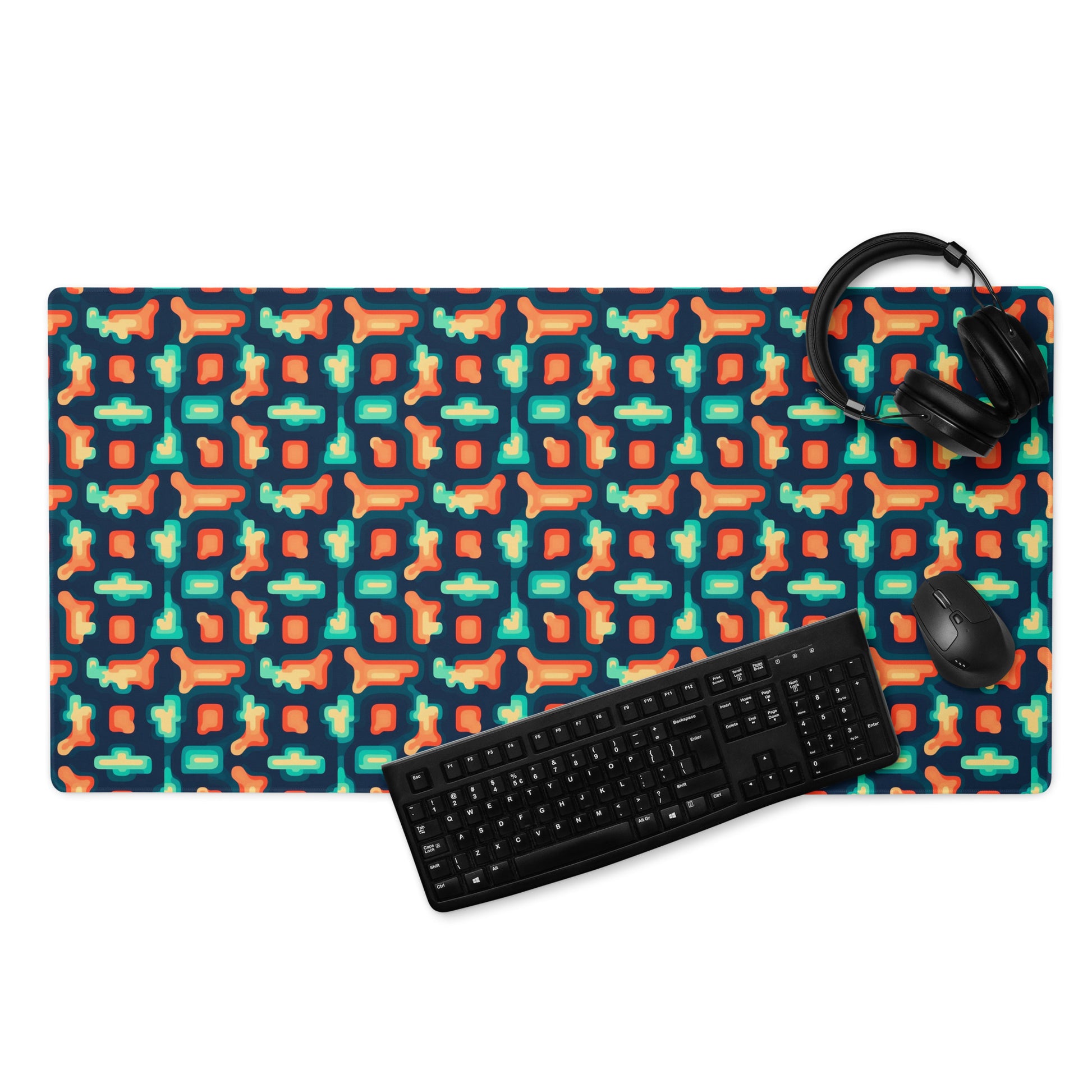 A 36" x 18" gaming desk pad with blue and orange puzzle pieces on a dark blue background. A keyboard, mouse, and headphones sit on it.