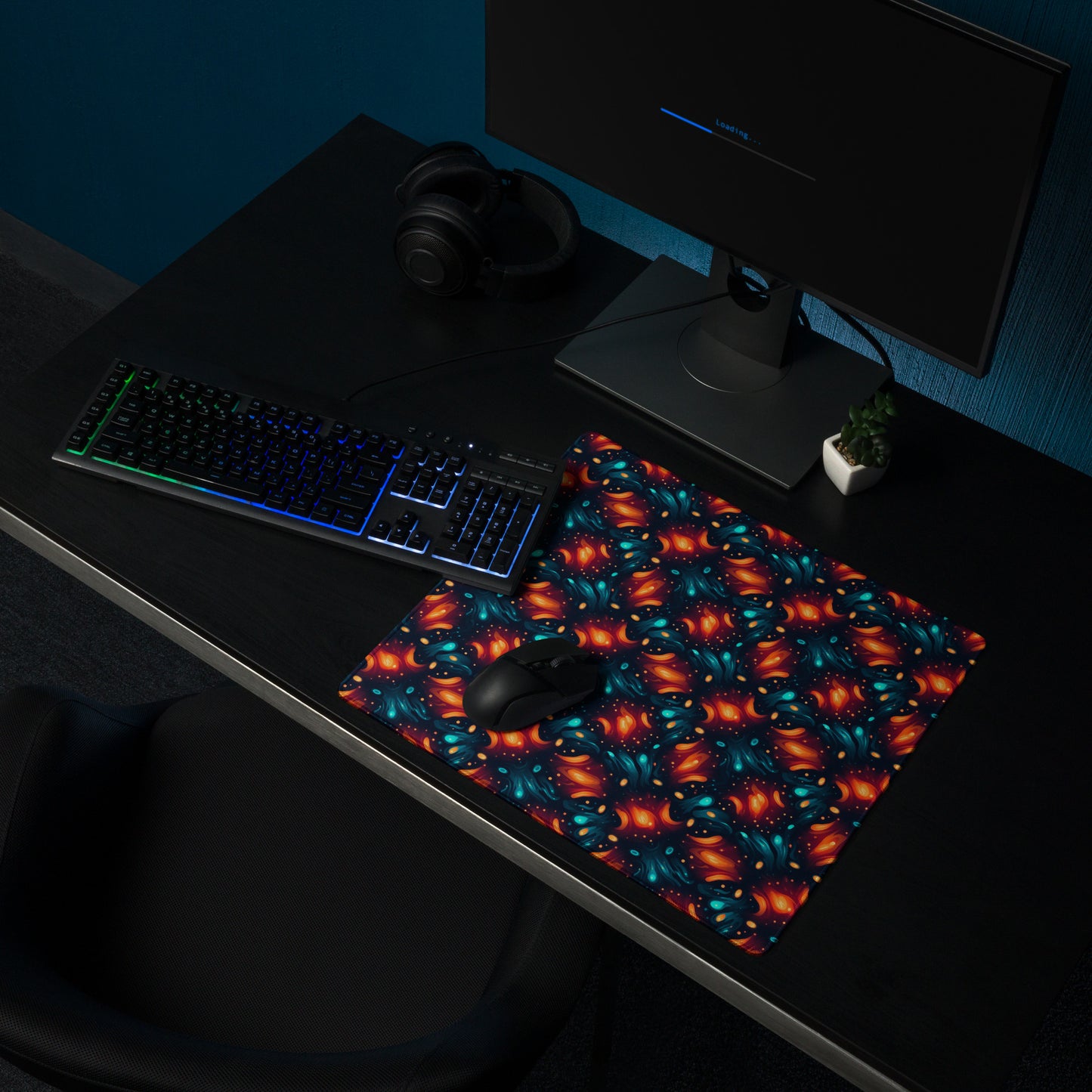 A 18" x 16" desk pad with a blue and orange abstract cross hatch pattern sitting on a desk.