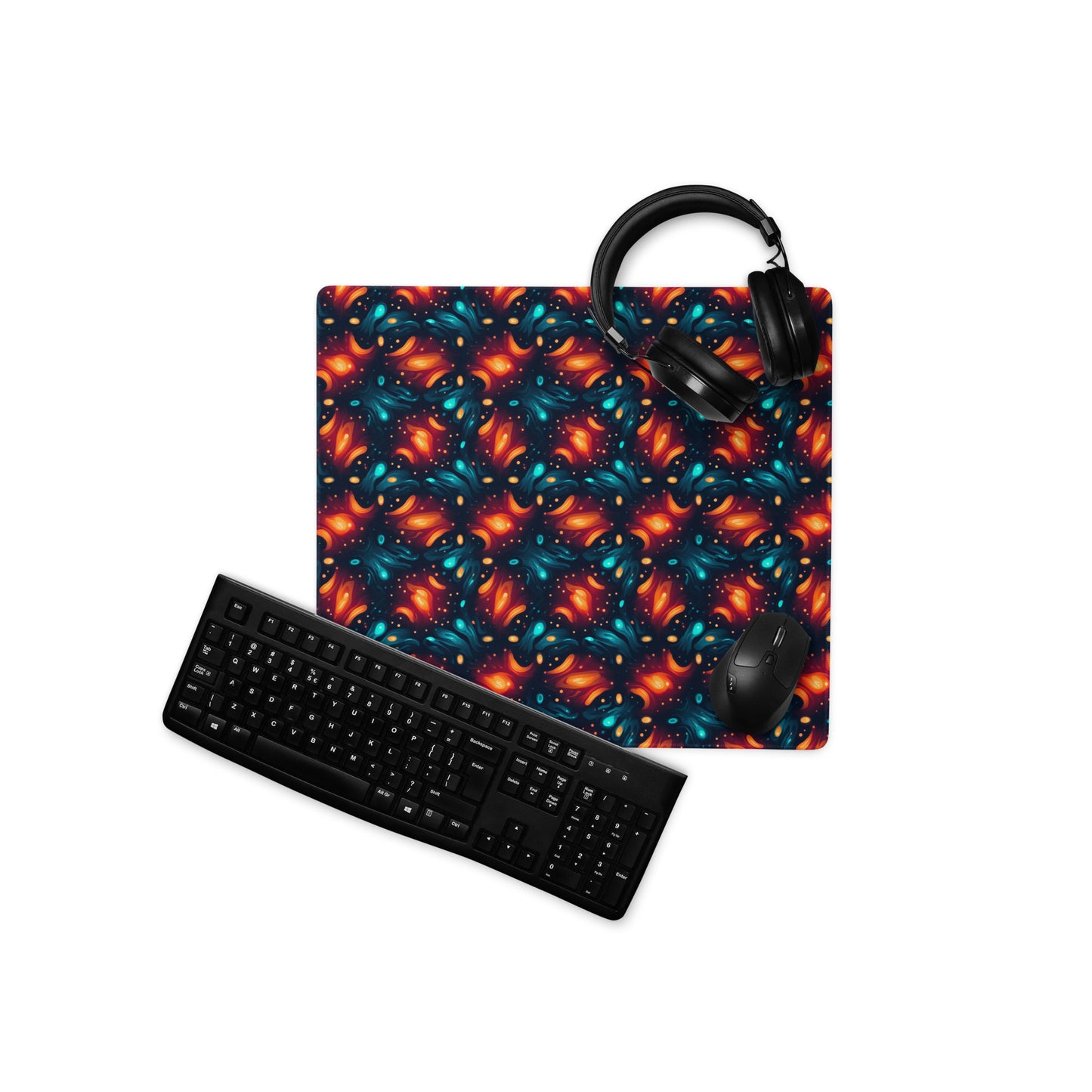 A 18" x 16" desk pad with a blue and orange abstract cross hatch pattern. With a keyboard, mouse, and headphones sitting on it.