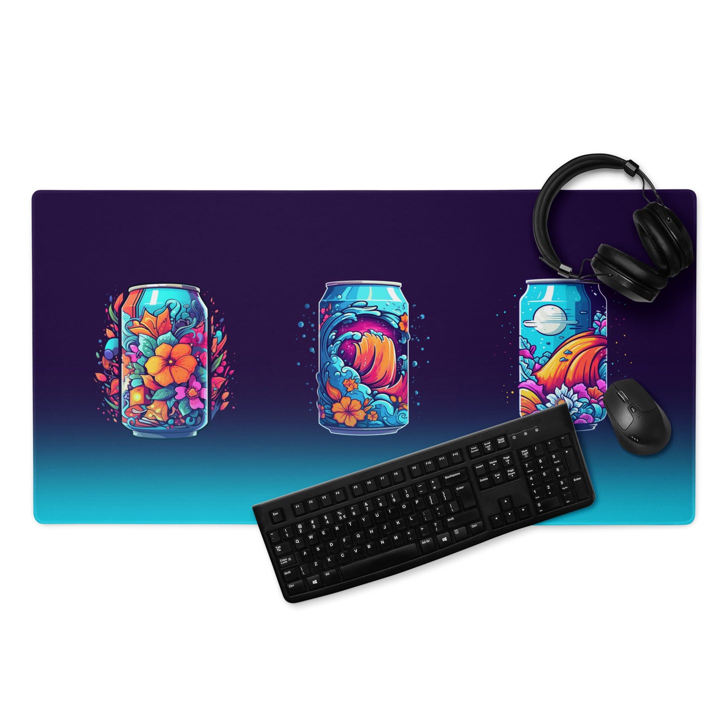 A 36" x 18" desk pad three soda cans that have a floral, wave, or space design. With a keyboard, mouse, and headphones sitting on it.