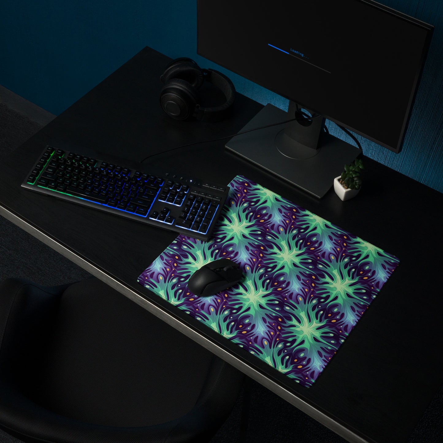 A 36" x 18" desk pad with a green and blue abstract pattern sitting on a desk.