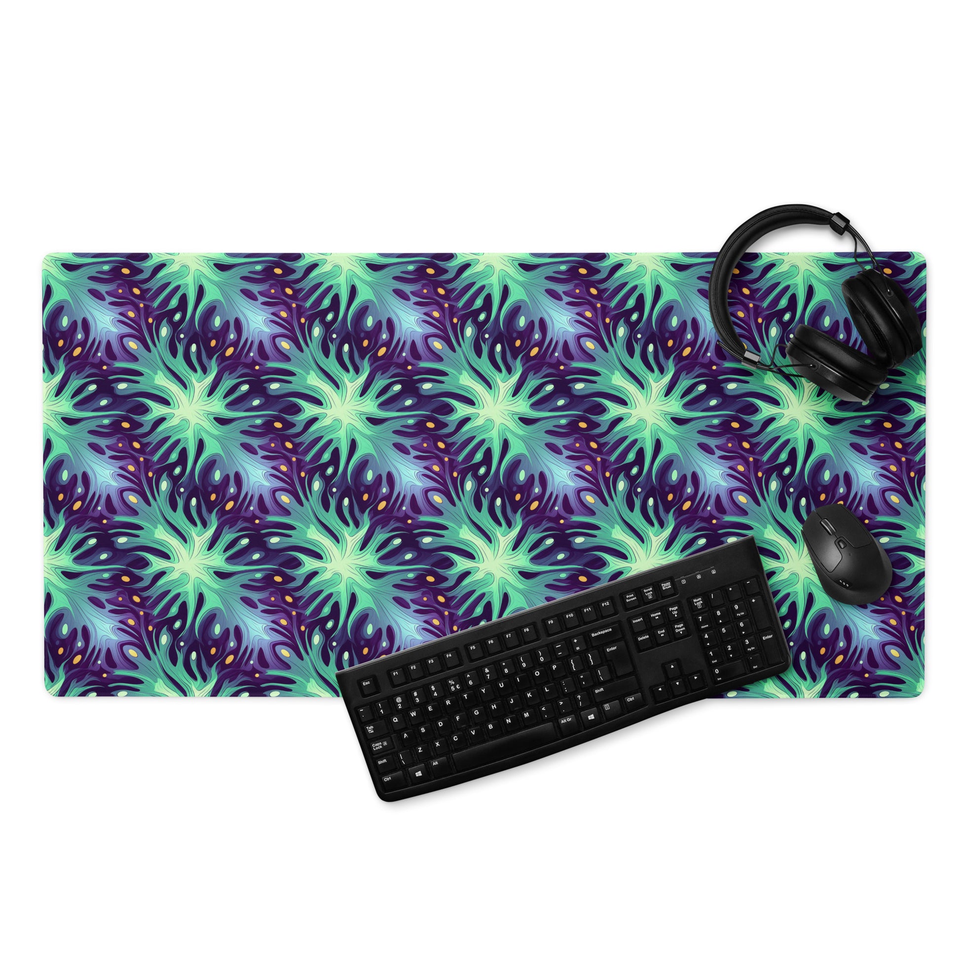 A 36" x 18" desk pad with a green and blue abstract pattern. With a keyboard, mouse, and headphones sitting on it.