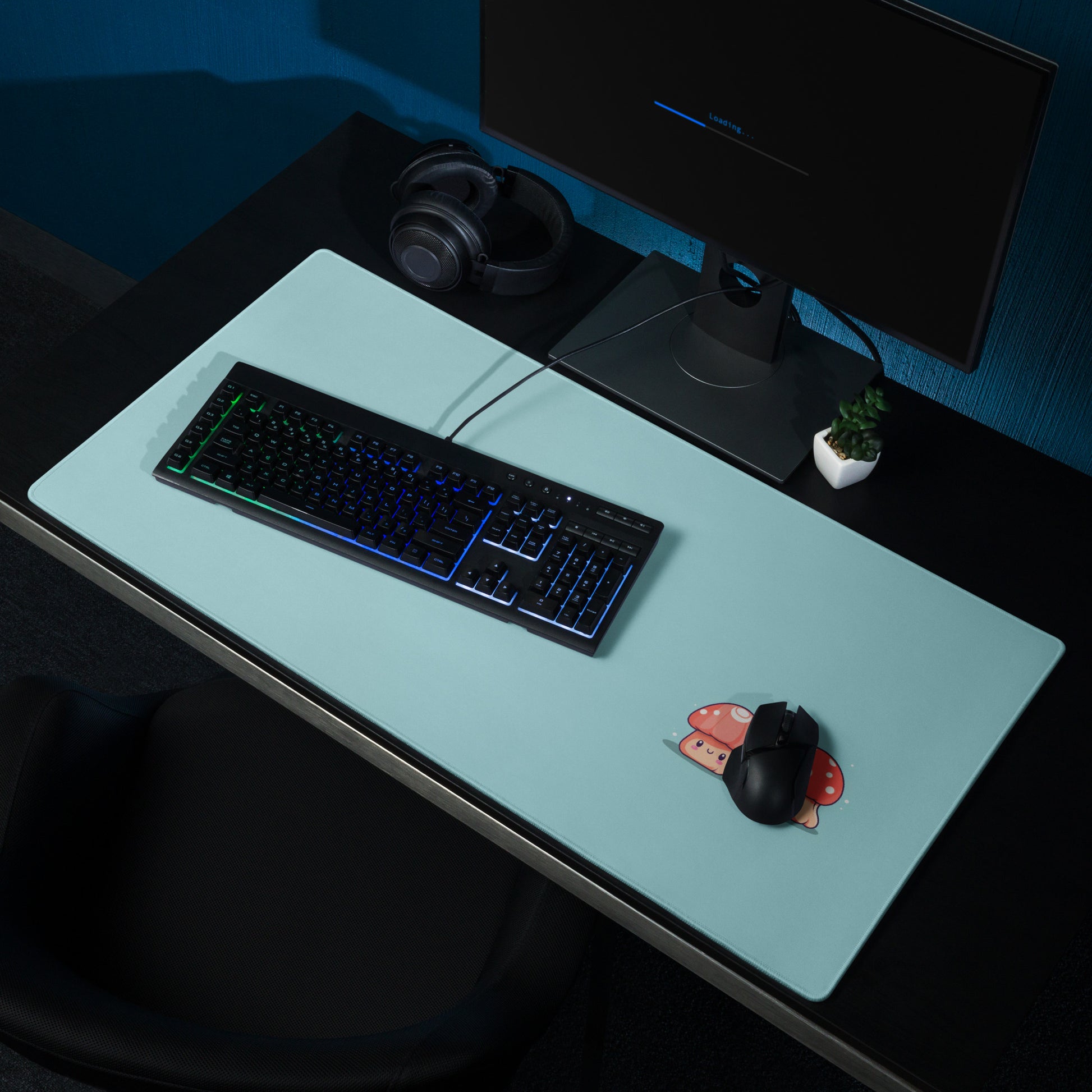 A gaming desk pad with two kawaii mushrooms on a blue background. A keyboard and mouse sit on top of it.