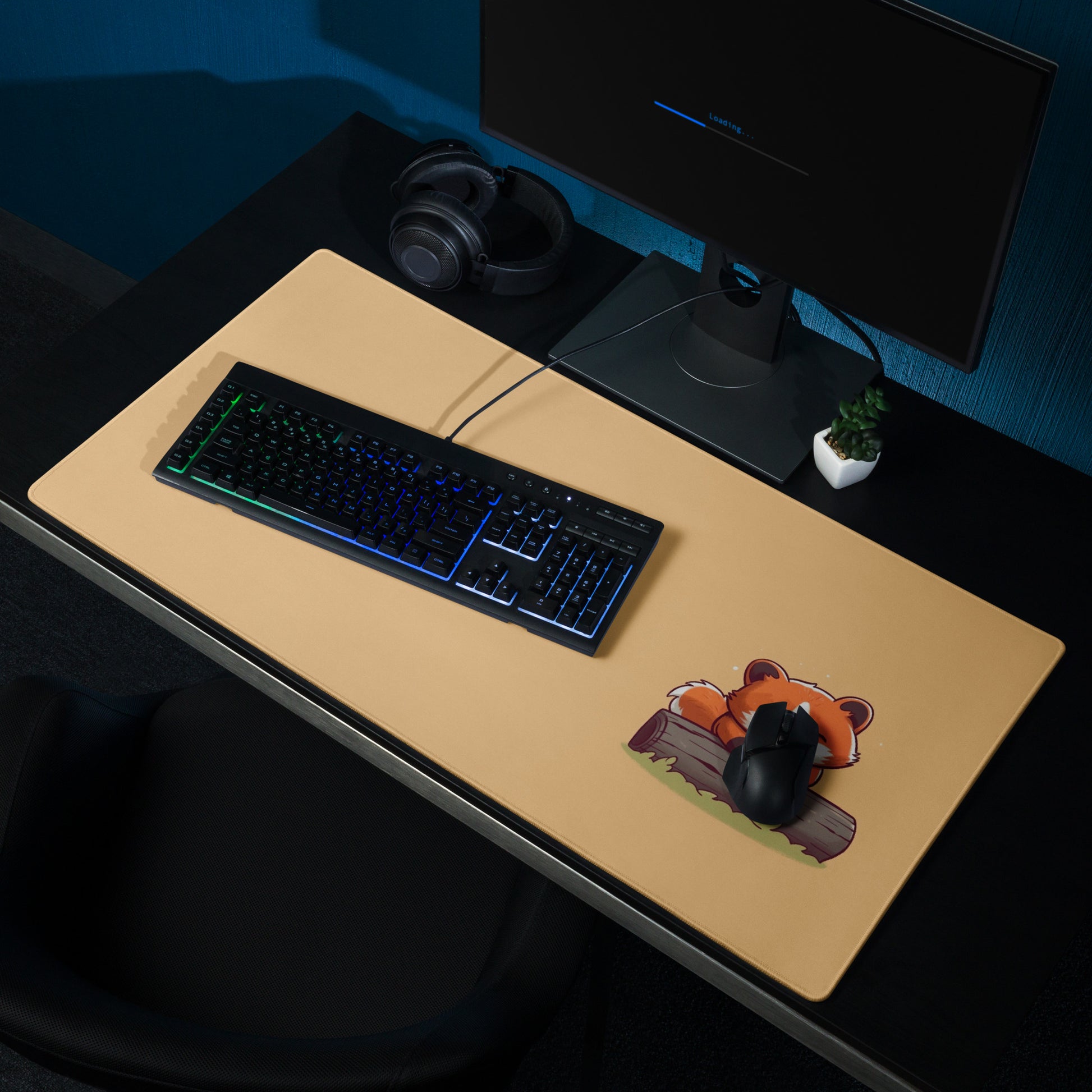 A gaming desk pad with a kawaii red panda smiling and leaning on a log. The background of the desk mat is orange. A keyboard and mouse sit on top of it.