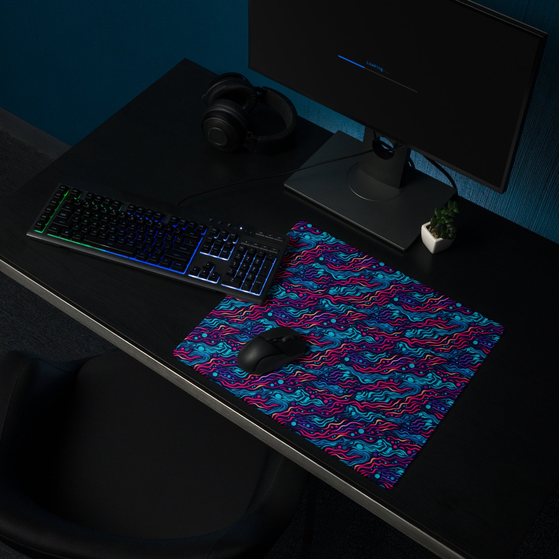 A 18" x 16" desk pad with wavy blue and pink pattern sitting on a desk