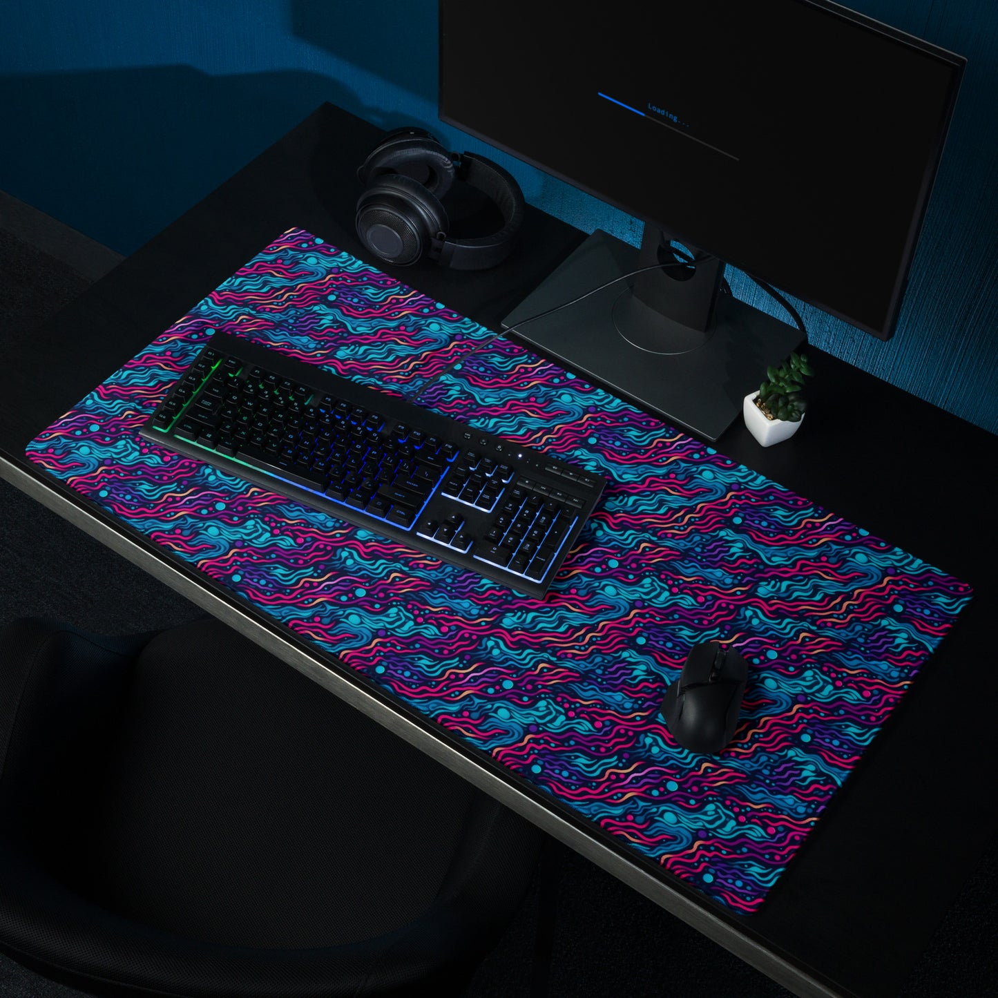 A 36" x 18" desk pad with wavy blue and pink pattern sitting on a desk.