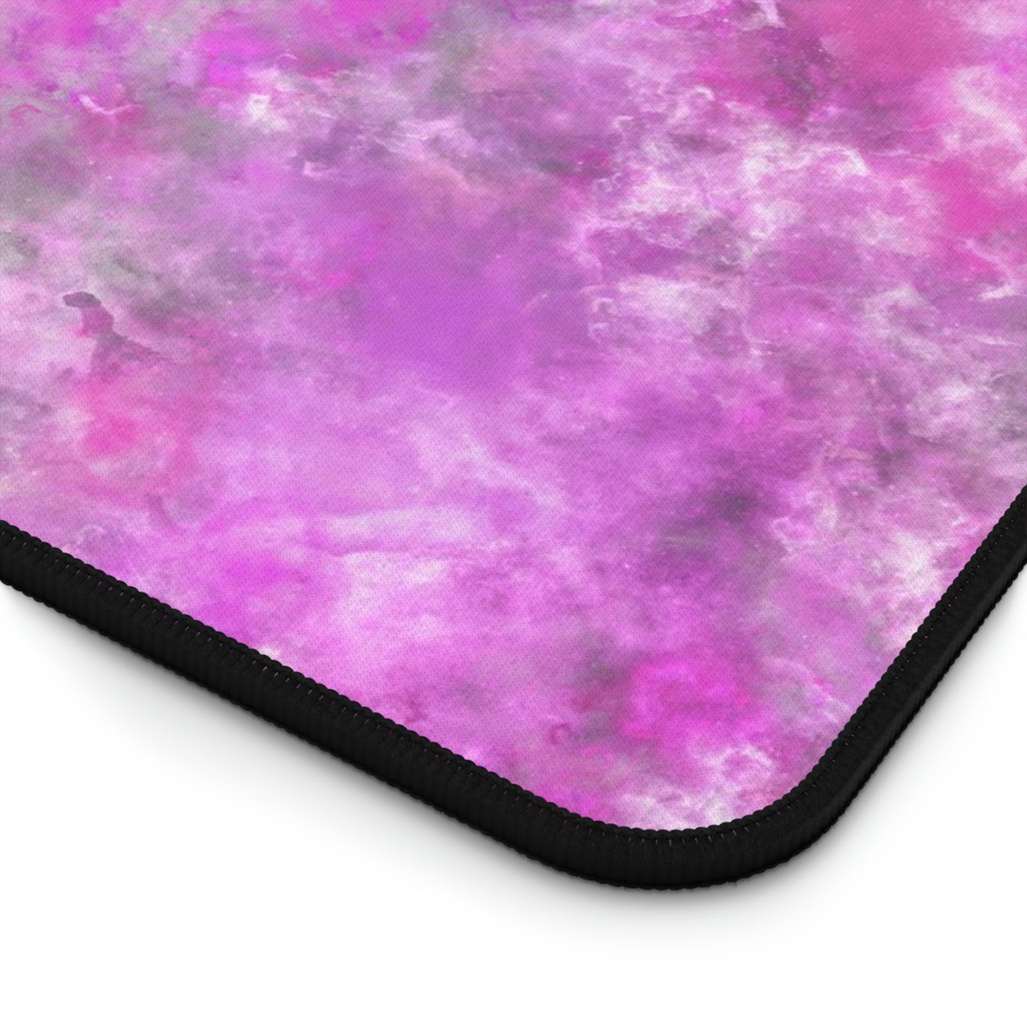 The corner of a 12" x 18" desk mat with a fluffy mix of pink, white, and gray.