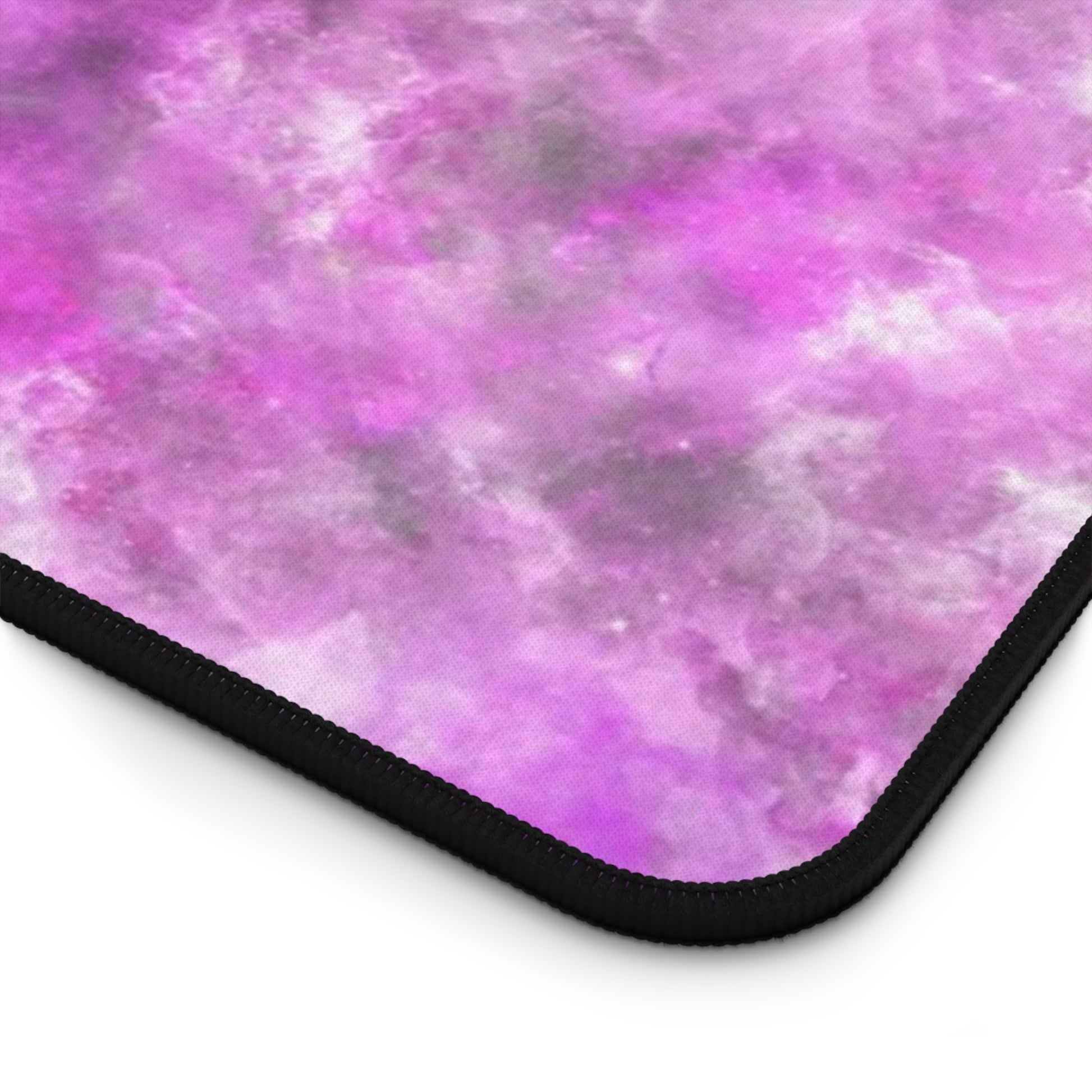 The corner of a 31" x 15.5" desk mat with a fluffy mix of pink, white, and gray.