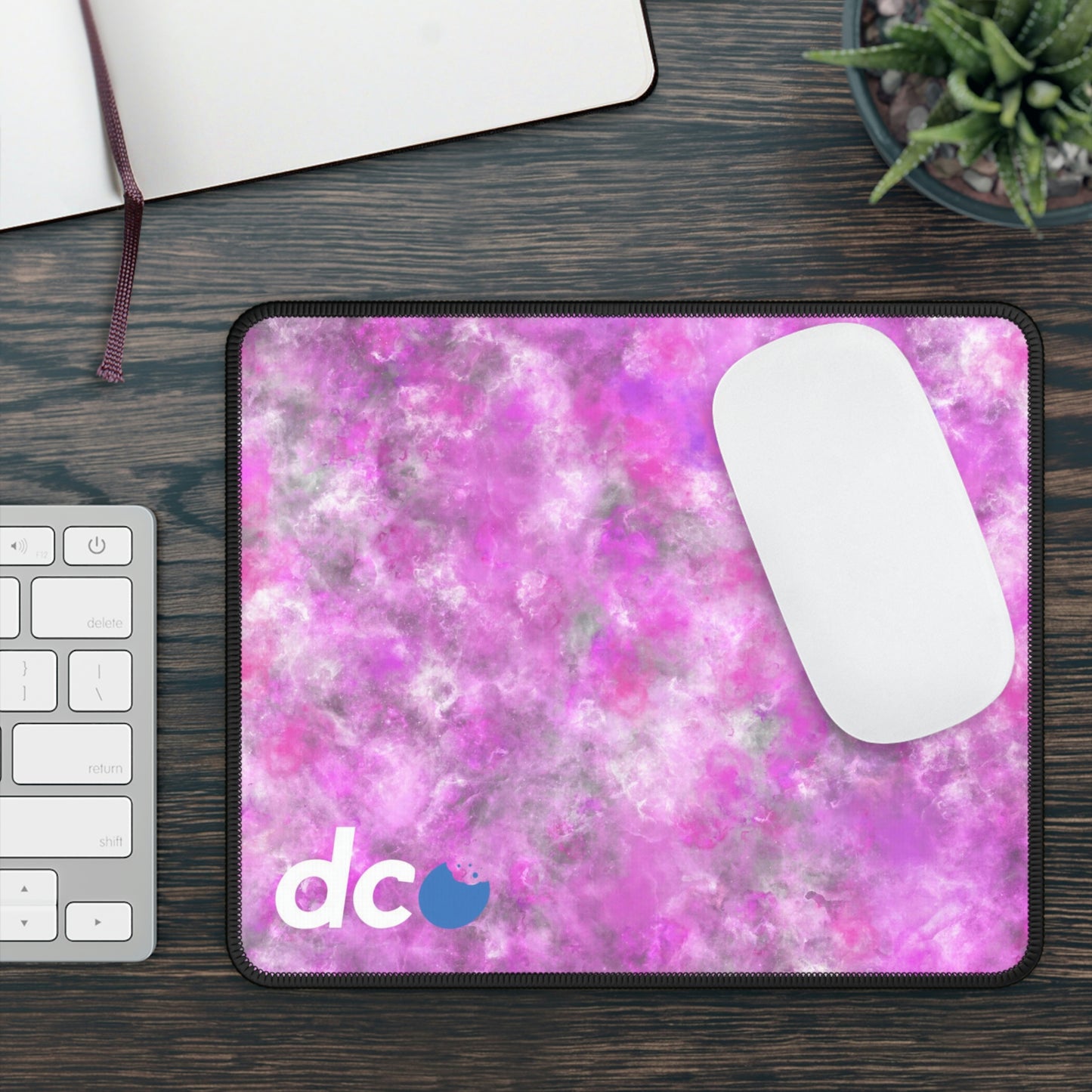 A gaming mouse pad with a fluffy mix of pink, white, and gray. A mouse sits on top of it.