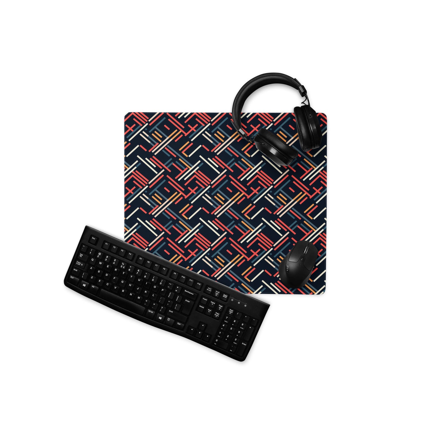 An 18" x 16" gaming desk pad with red, blue, white, and orange lines on a black background. A keyboard, mouse, and headphones sit on it.