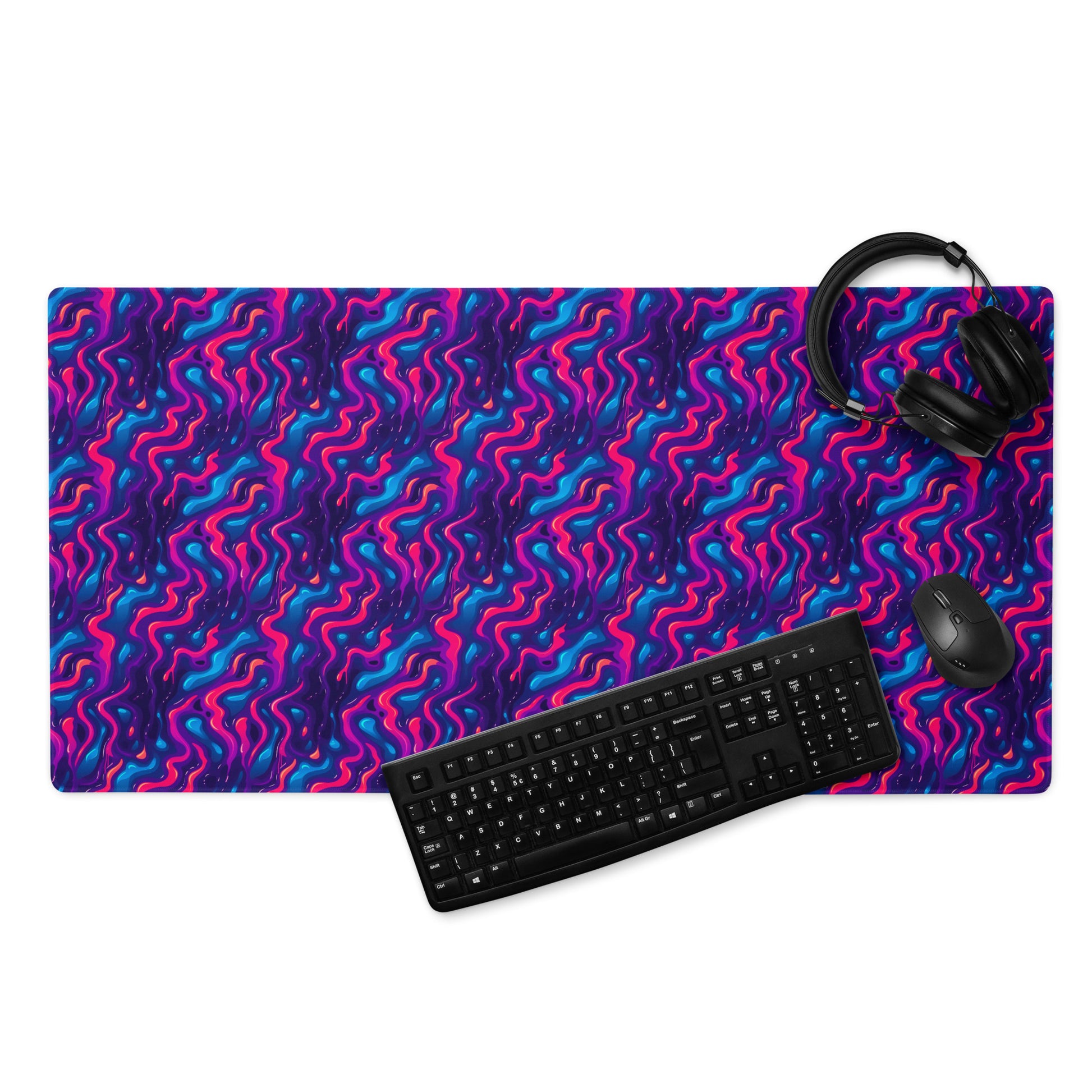 A 36" x 18" desk pad with a pink, blue and purple wavy pattern. With a keyboard, mouse, and headphones sitting on it.