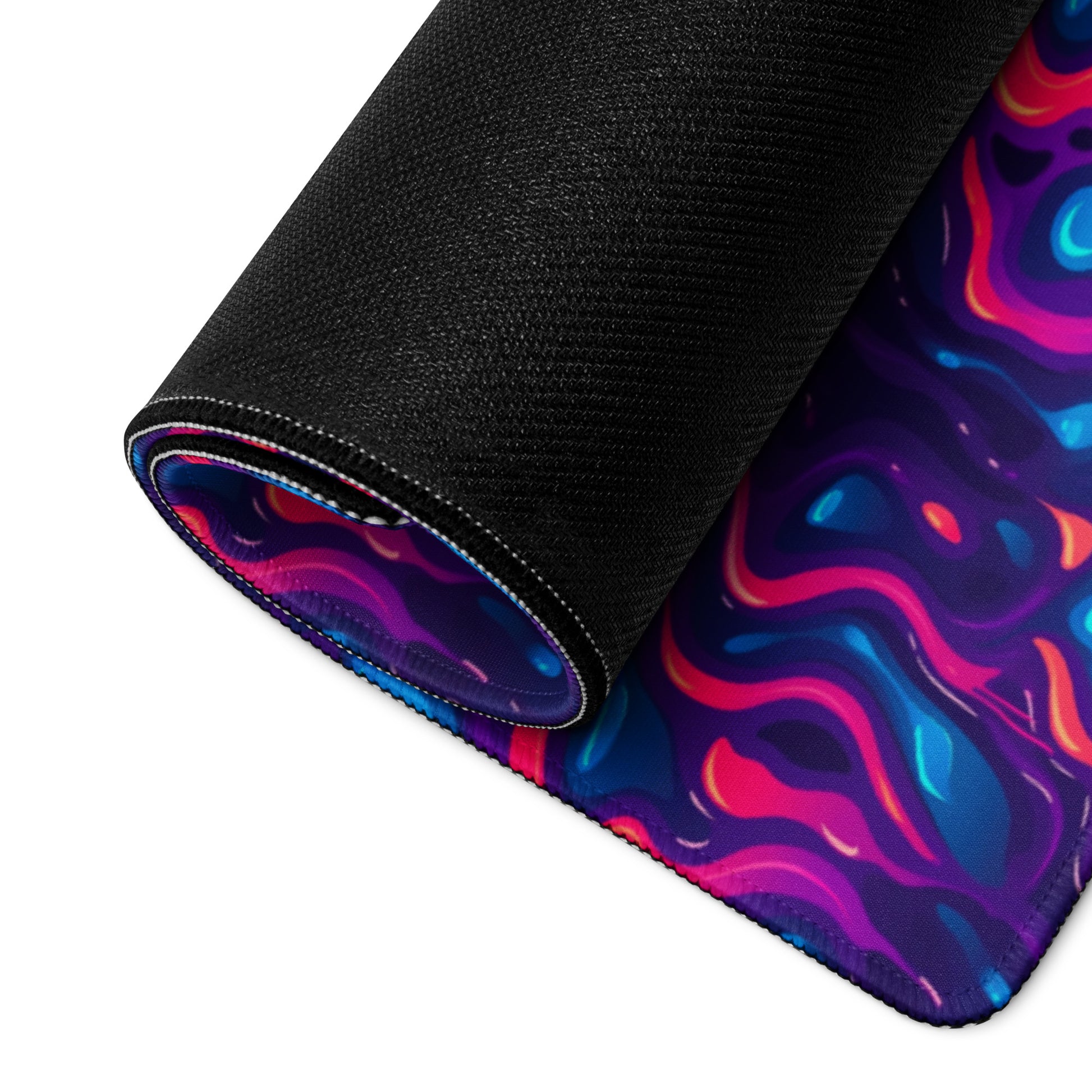 A 36" x 18" desk pad with a pink, blue and purple wavy pattern rolled up.