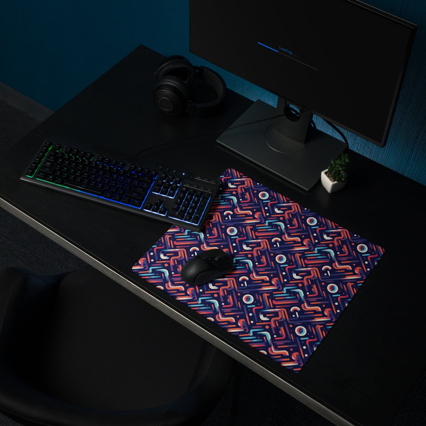 An 18" x 16" gaming desk pad with blue, orange, and purple lines on a dark blue background. A keyboard and mouse sit on it.