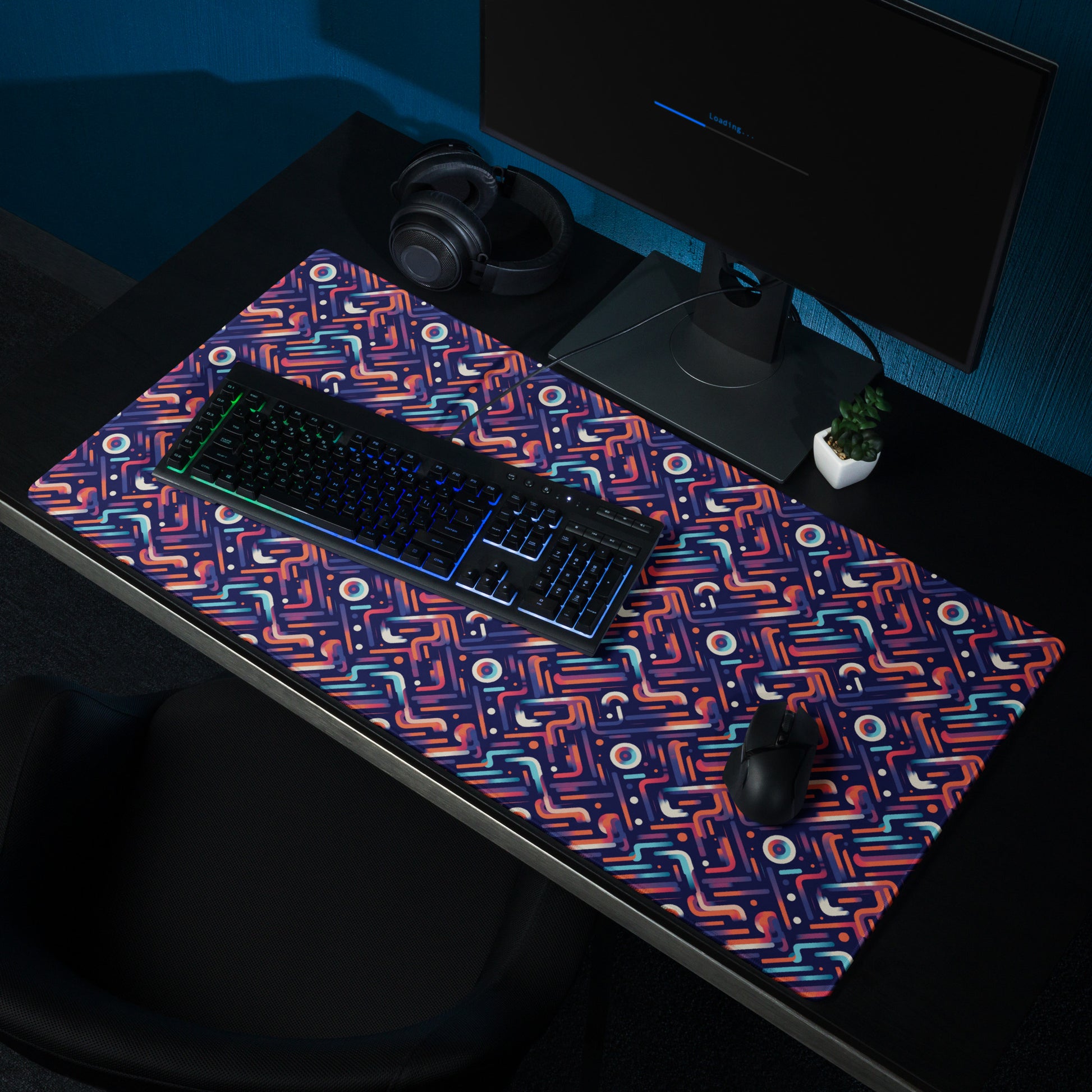A 36" x 18" gaming desk pad with blue, orange, and purple lines on a dark blue background. A keyboard and mouse sit on it.