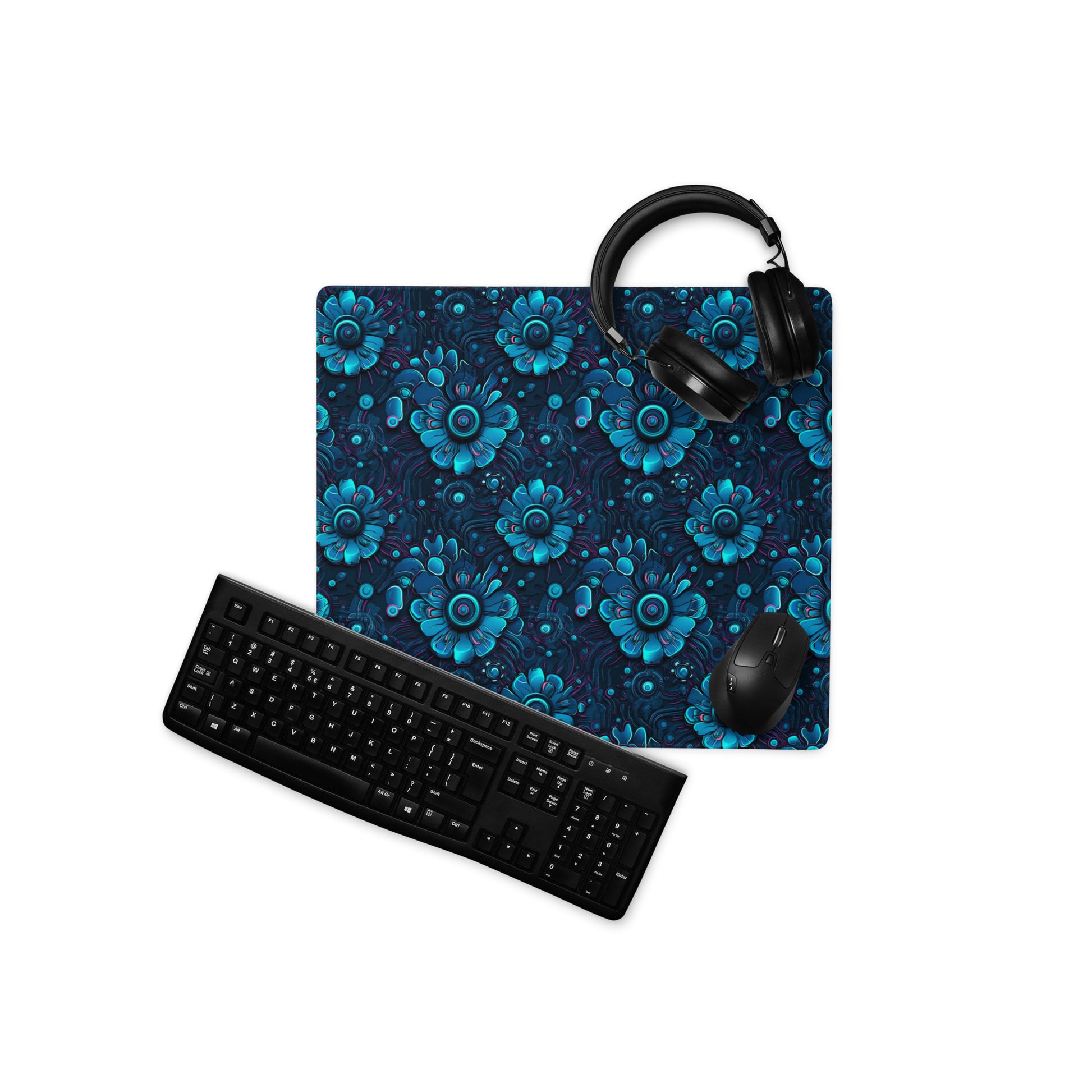 A 18" x 16" desk pad with a blue robotic floral pattern. With a keyboard, mouse, and headphones sitting on it.