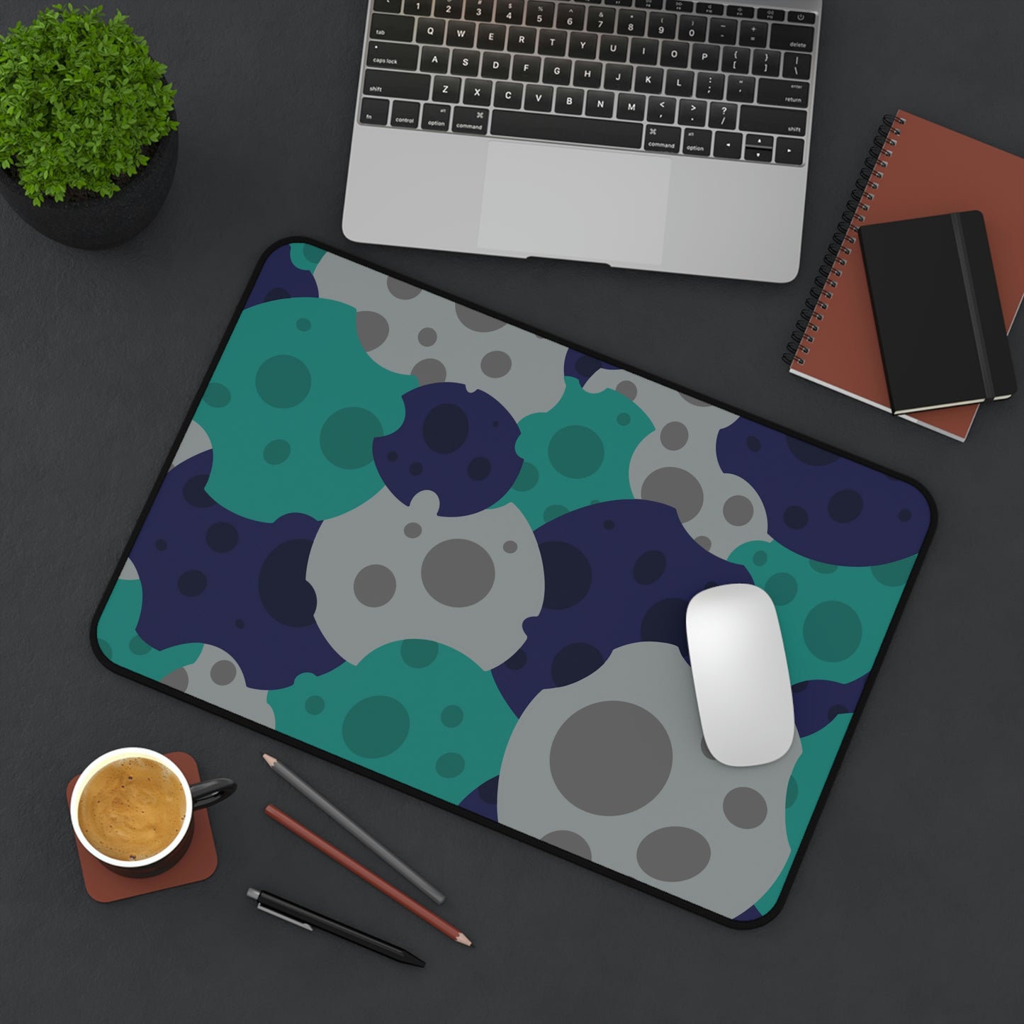 A 12" x 18" desk mat with gray, teal, and dark blue meteorites sitting at an angle.