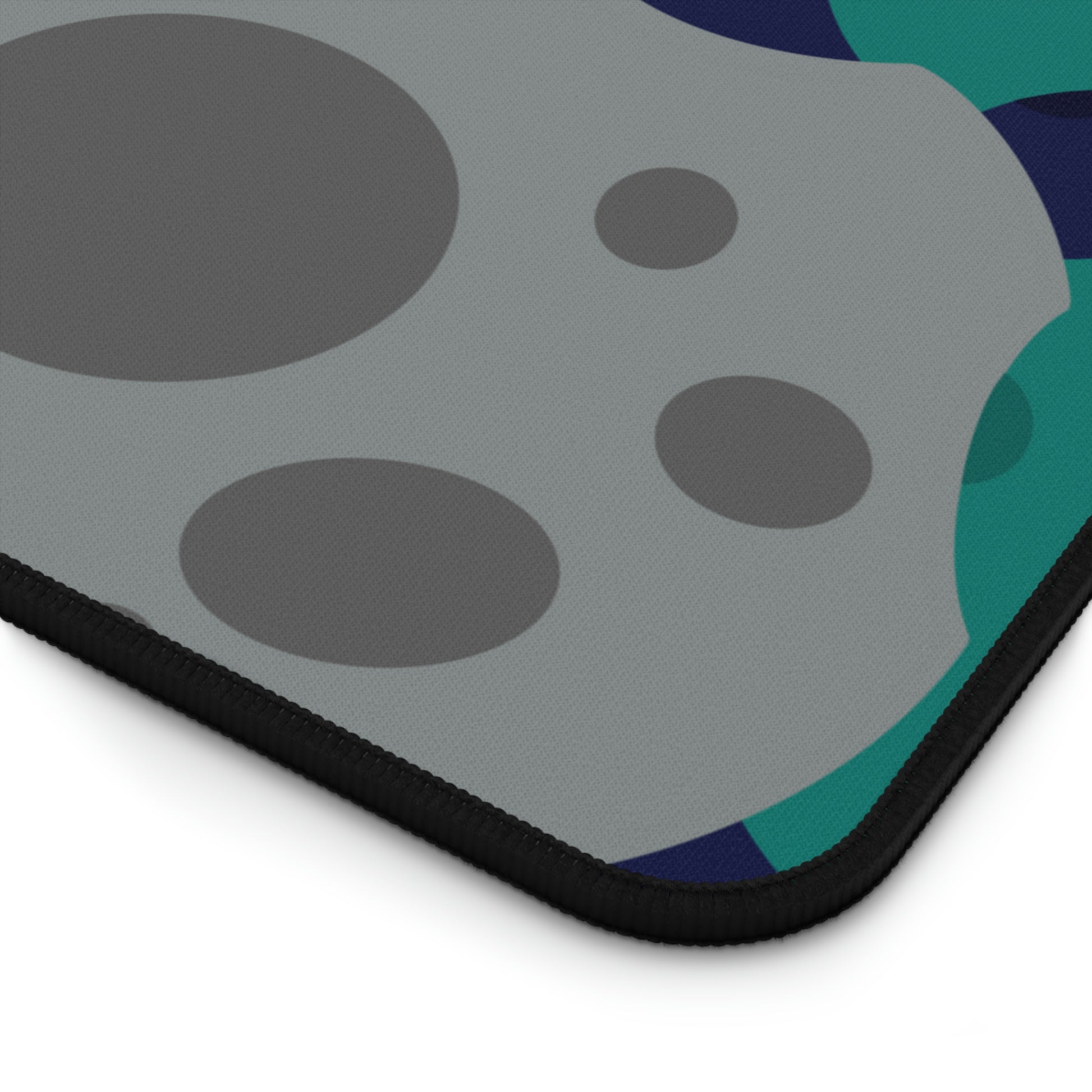 The corner of a 12" x 18" desk mat with gray, teal, and dark blue meteorites.