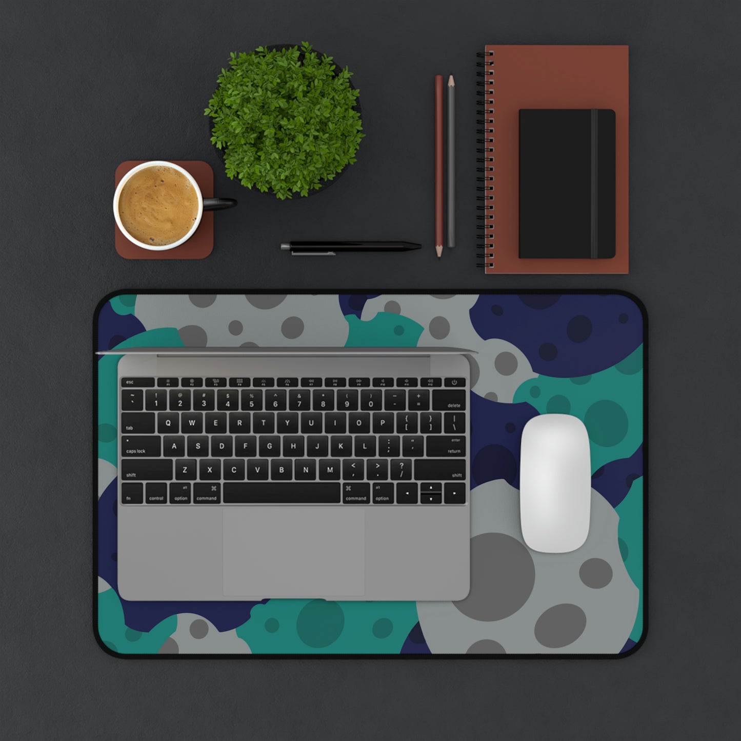 A 12" x 18" desk mat with gray, teal, and dark blue meteorites. A laptop and mouse sit on top of it.