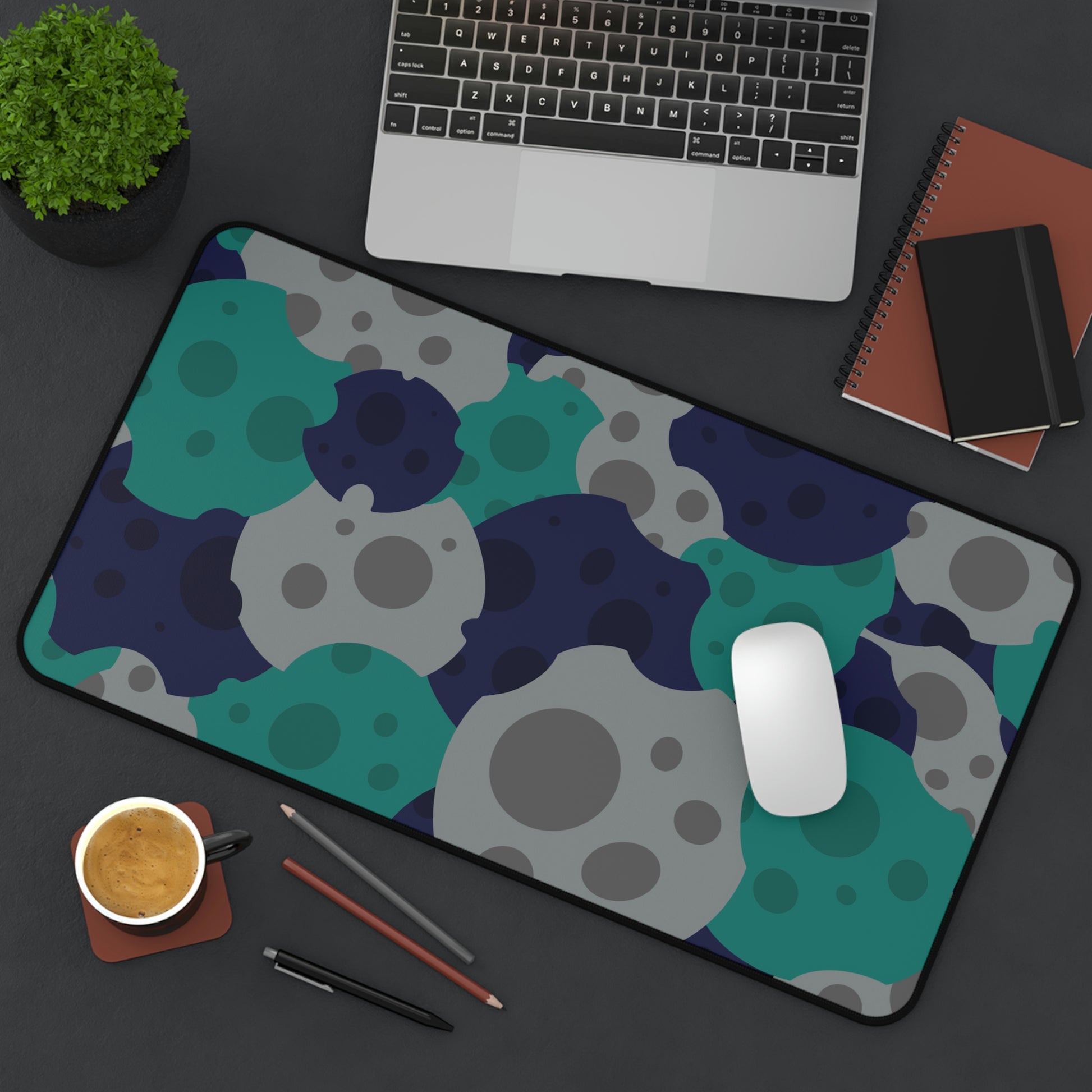 A 12" x 22" desk mat with gray, teal, and dark blue meteorites sitting at an angle.