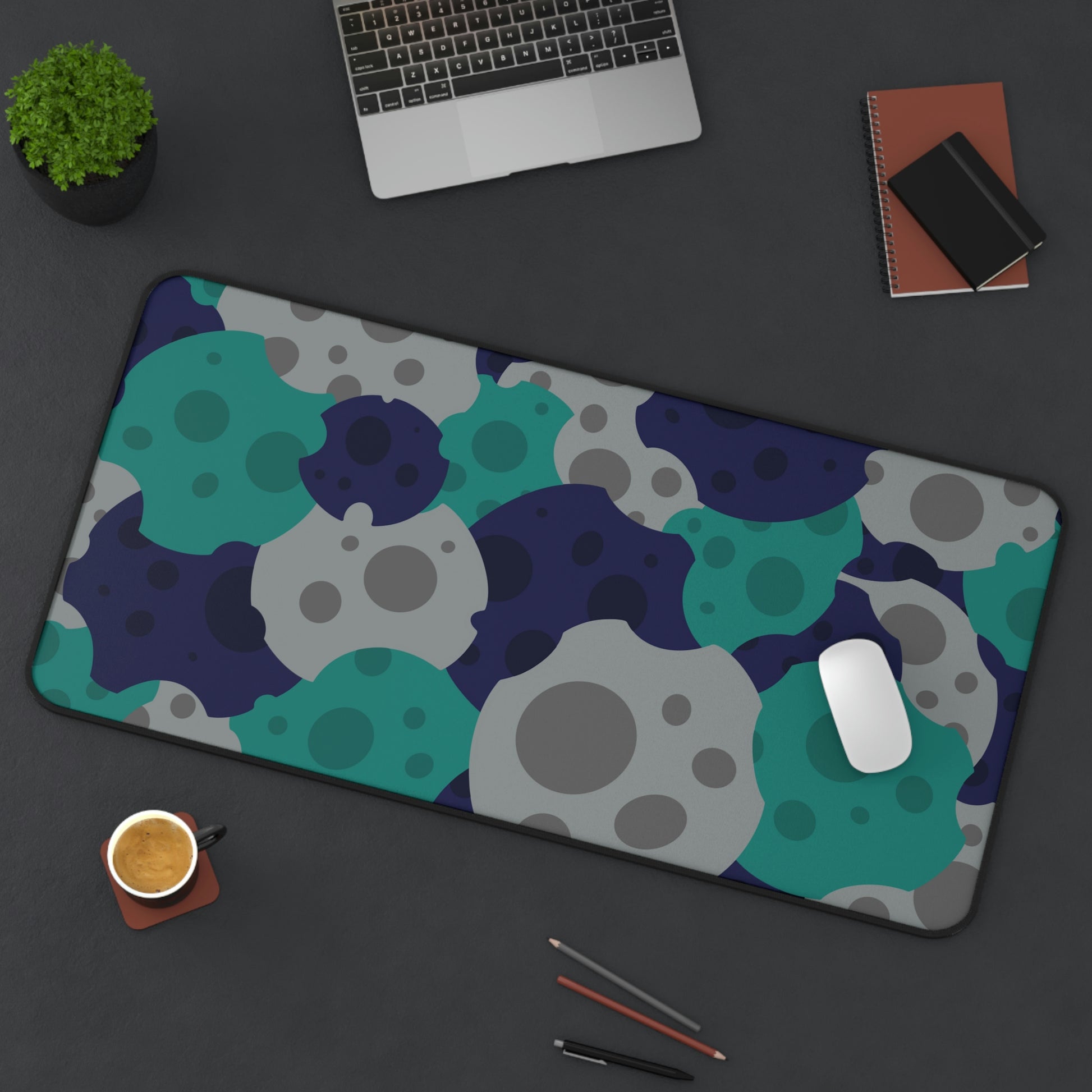 A 31" x 15.5" desk mat with gray, teal, and dark blue meteorites sitting at an angle.