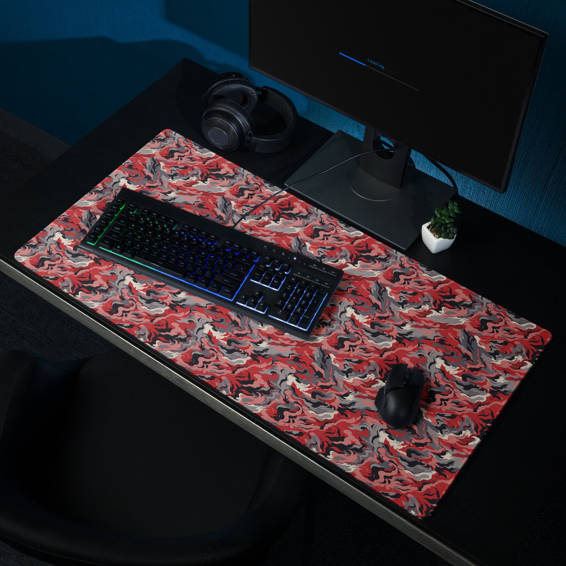 A 36" x 18" desk pad with a grey and red camo pattern sitting on a desk.