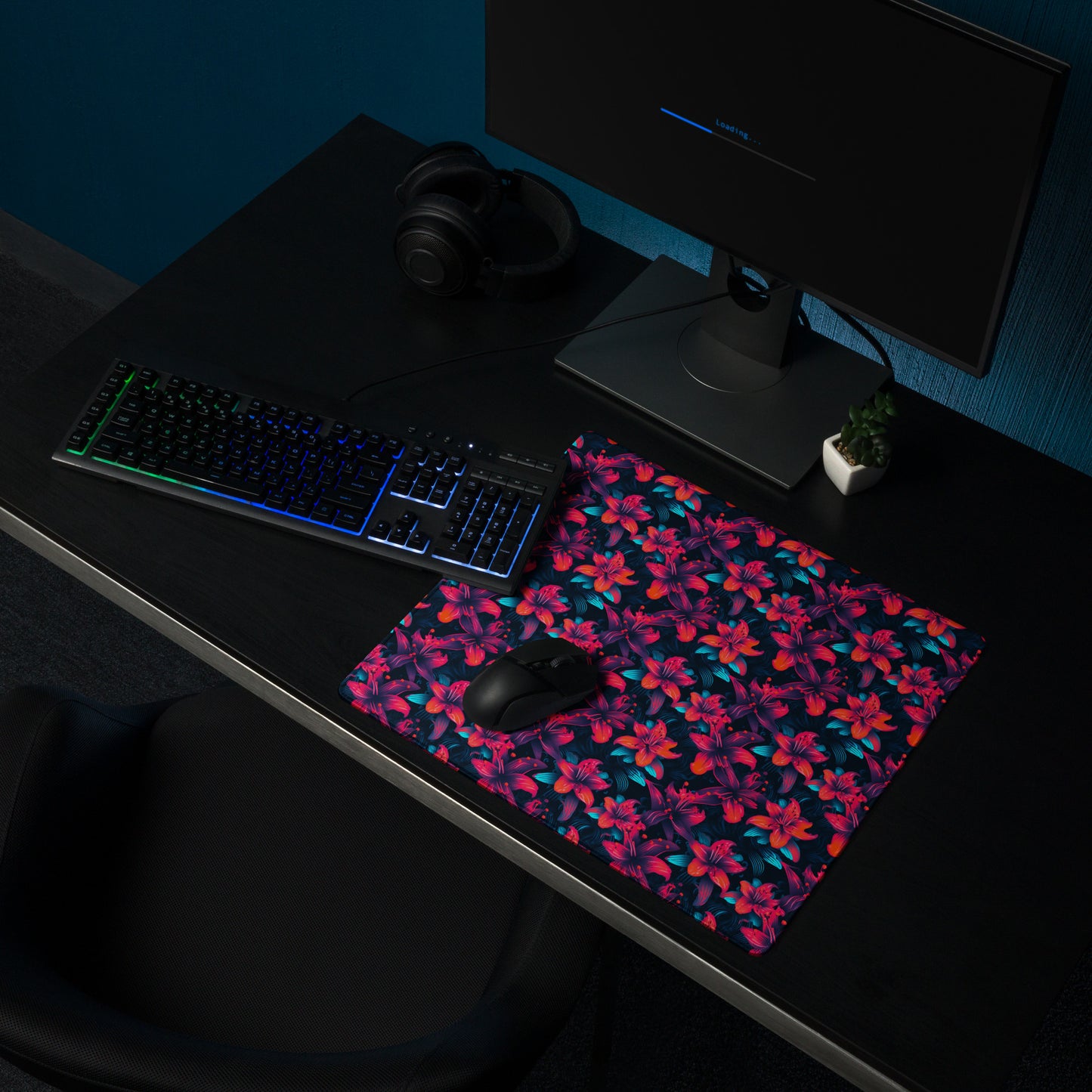 A 18" x 16" desk pad with a neon red and blue floral pattern sitting on a desk.