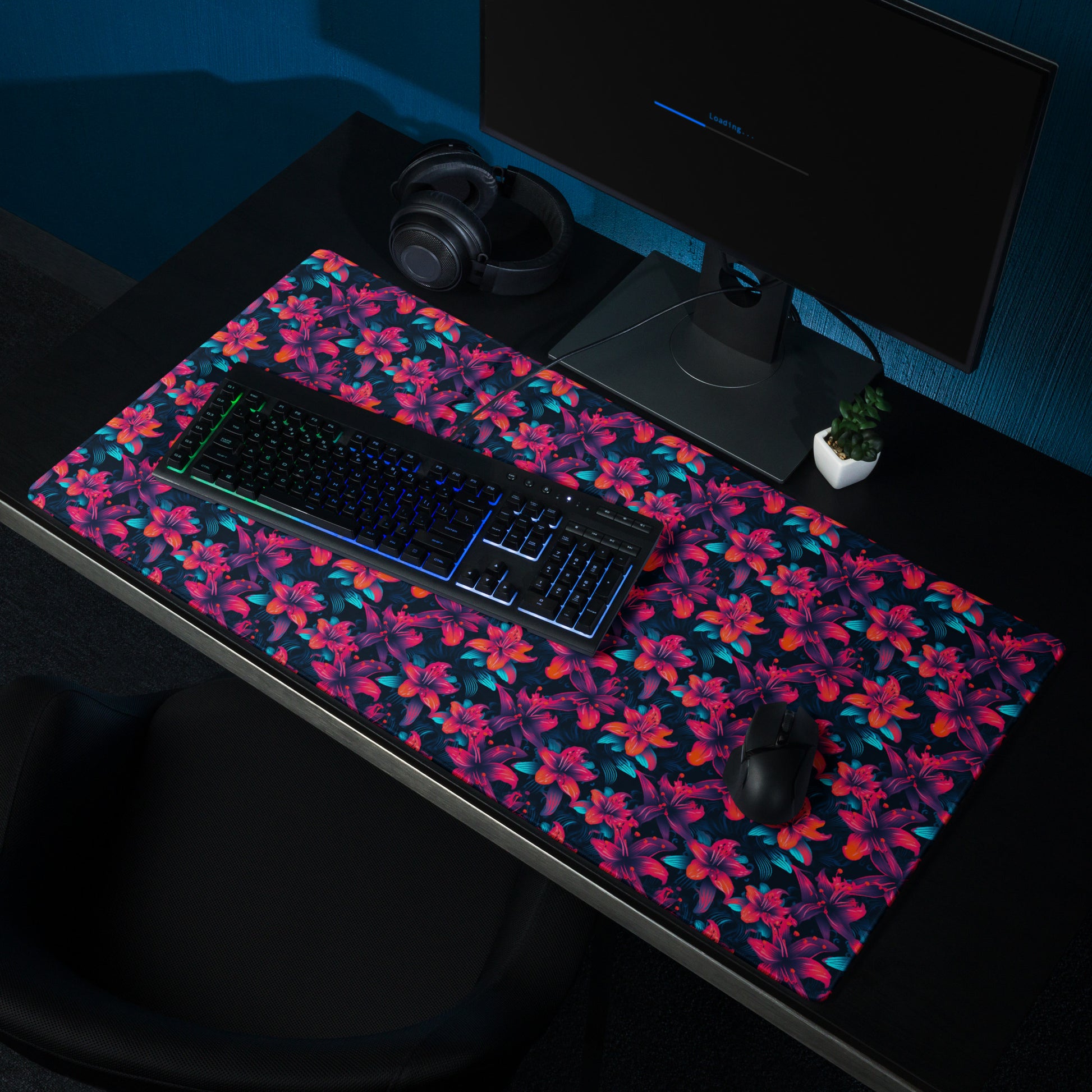 A 36" x 18" desk pad with a neon red and blue floral pattern sitting on a desk.