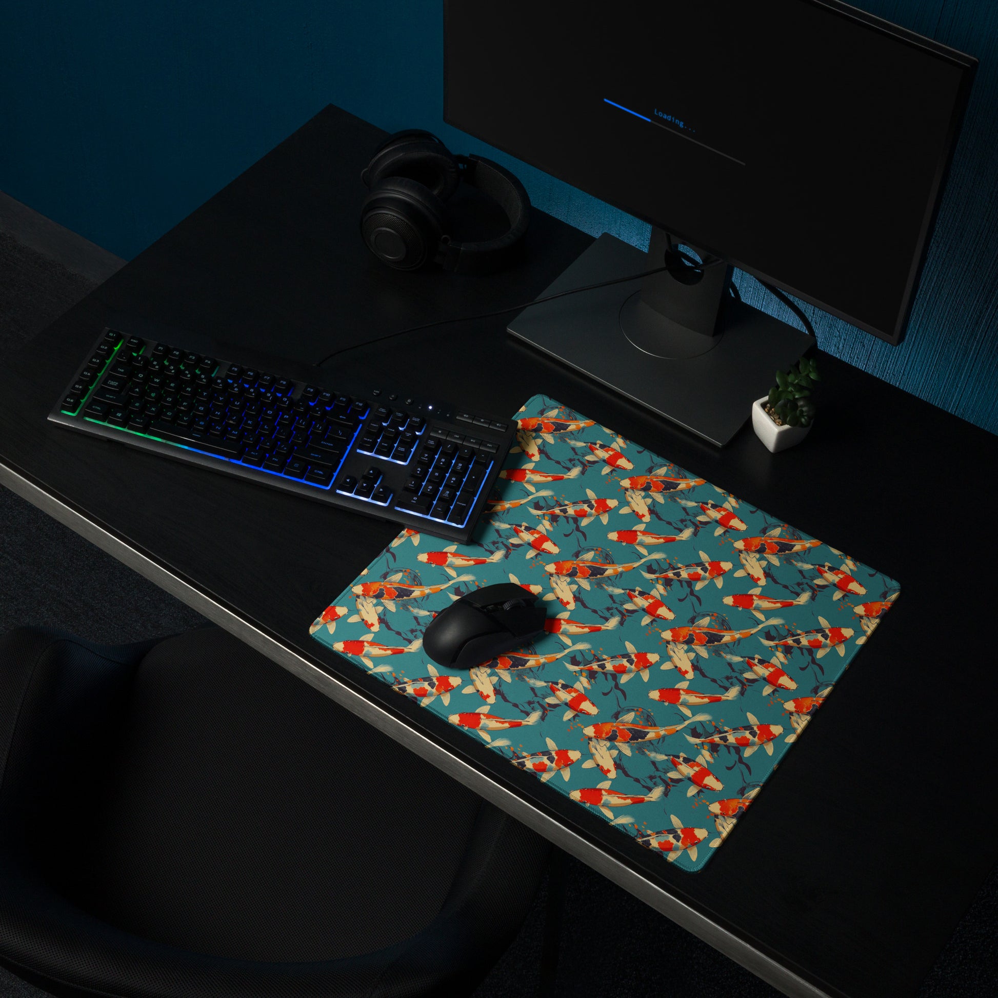 An 18" x 16" gaming desk pad with red koi fish on a blue background sitting on a desk. A keyboard and mouse sit on top of it.