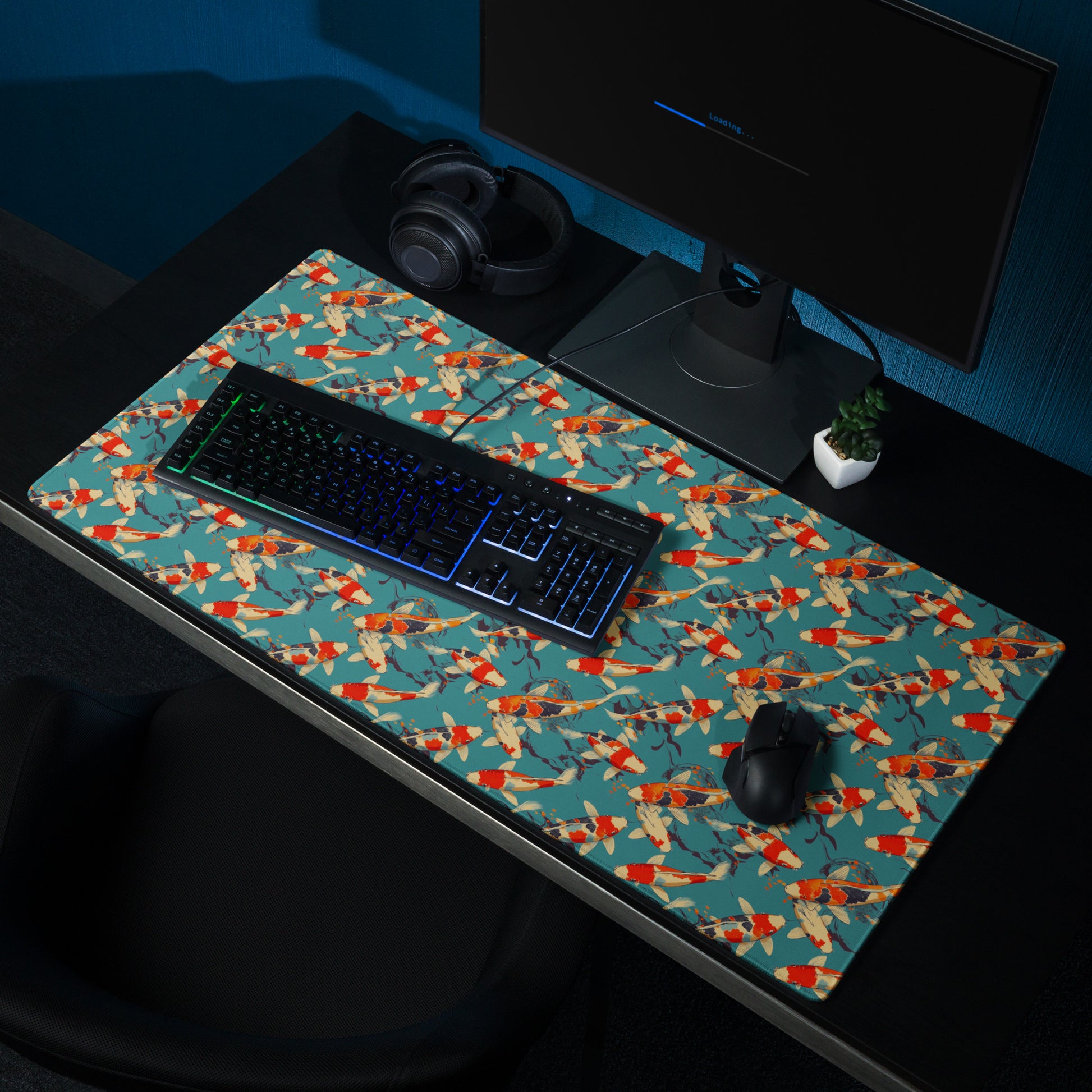 A 36" x 18" gaming desk pad with red koi fish on a blue background sitting on a desk. A keyboard and mouse sit on top of it.
