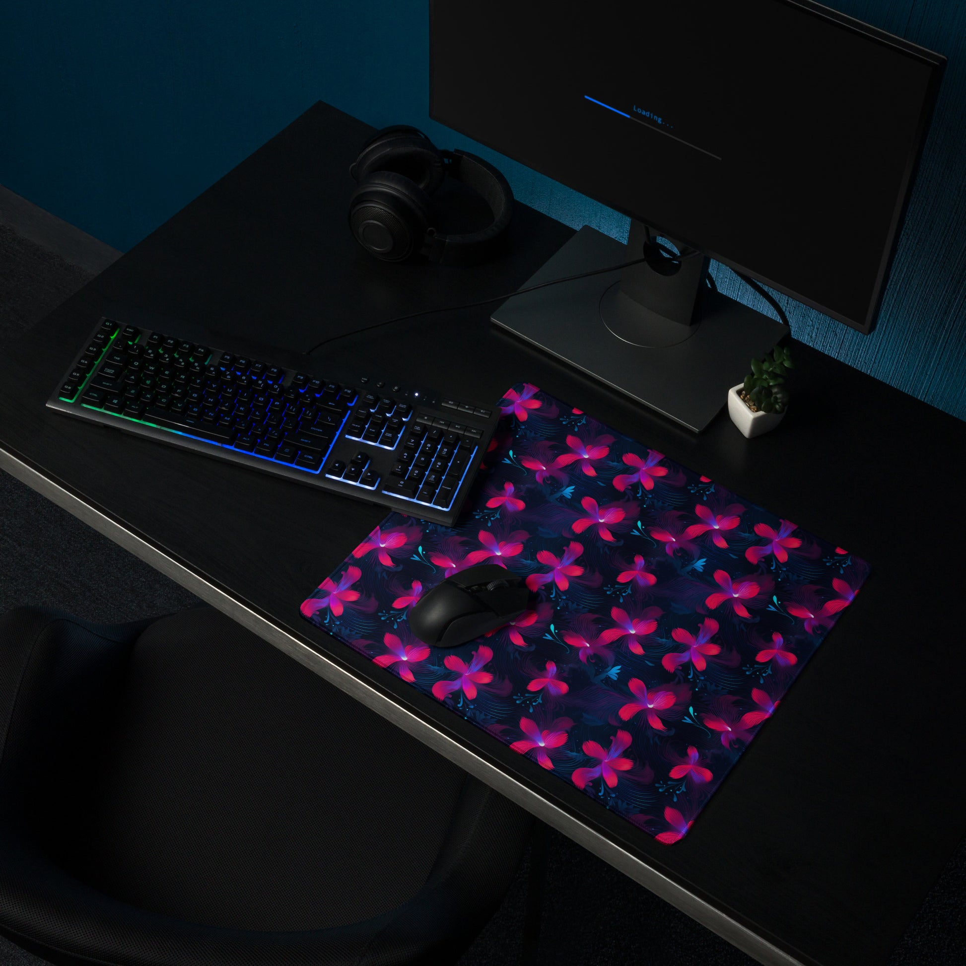 A 18" x 16" desk pad with neon pink and blue floral pattern sitting on a desk.