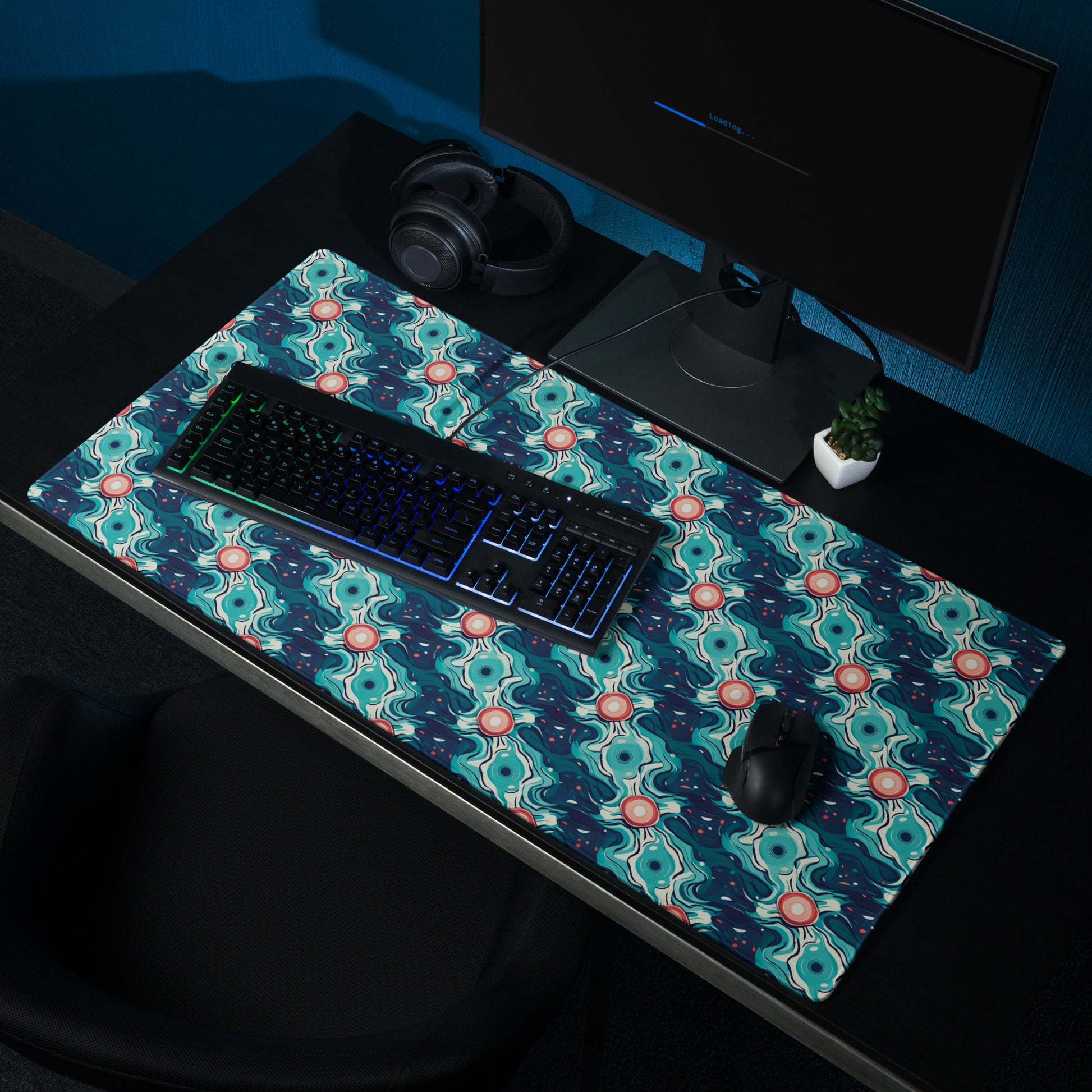 A 36" x 18" desk pad with a teal abstract wavy pattern sitting on a desk.
