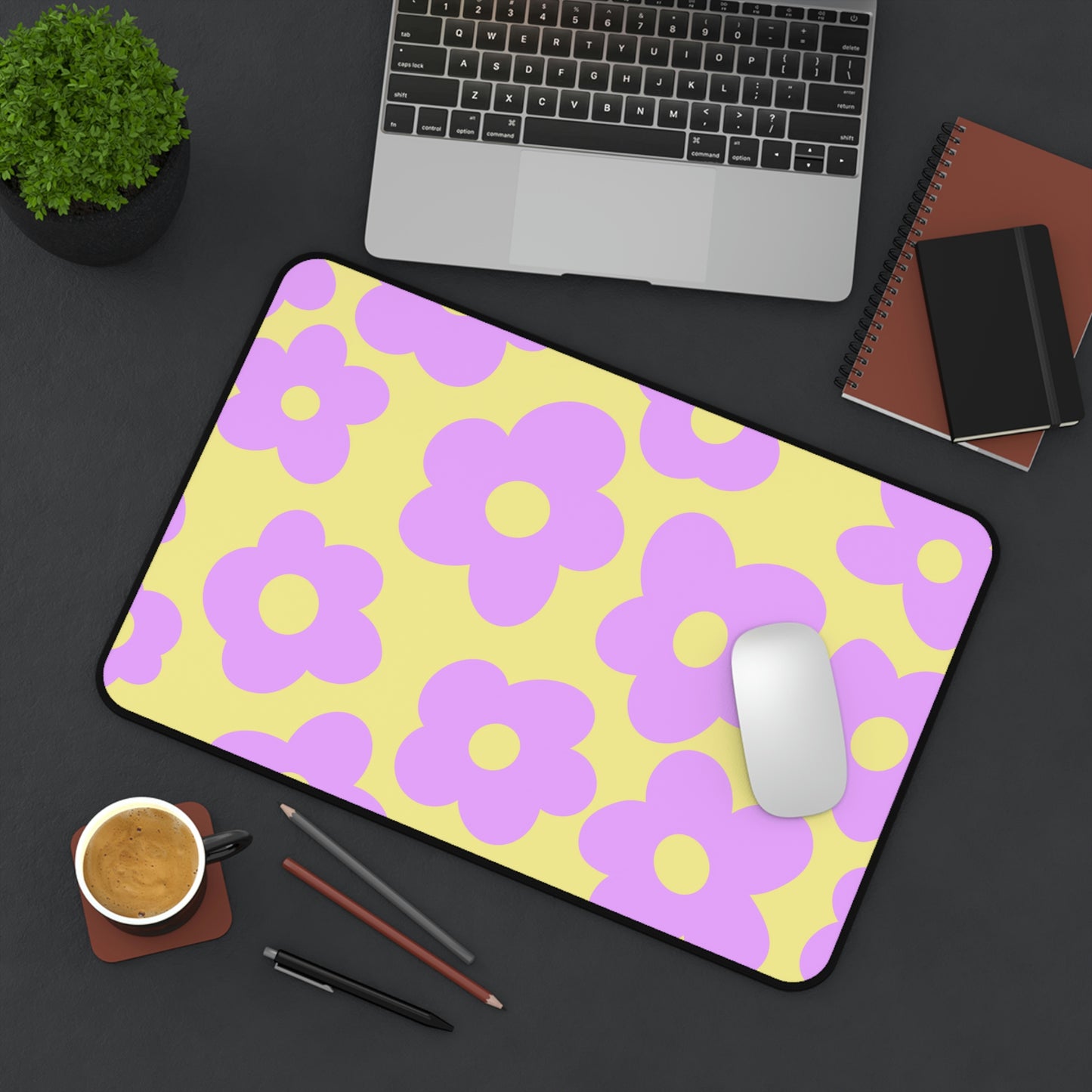 A 12" x 18" desk mat with purple flowers on a yellow background sitting at an angle.