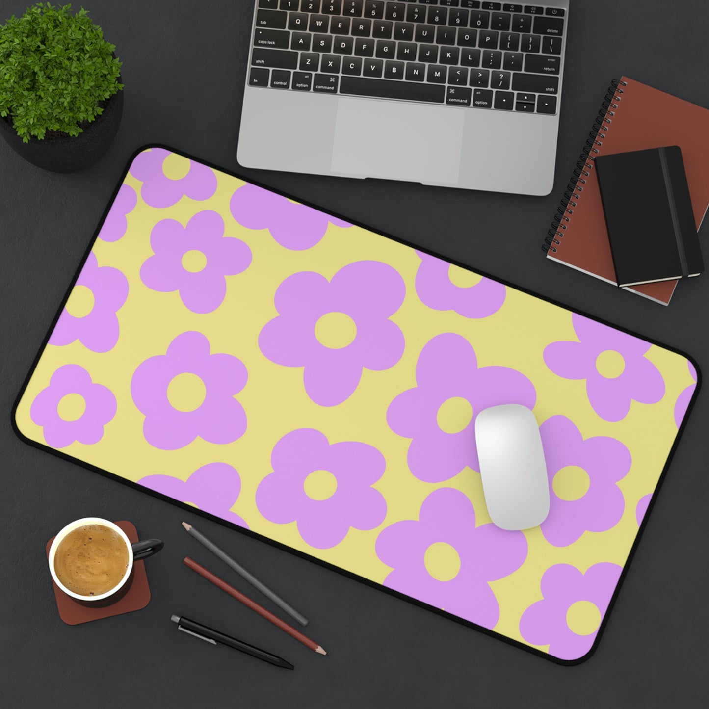 A 12" x 22" desk mat with purple flowers on a yellow background sitting at an angle.