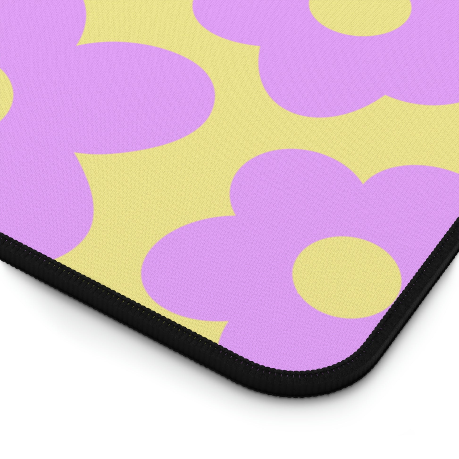 The corner of a 12" x 22" desk mat with purple flowers on a yellow background.