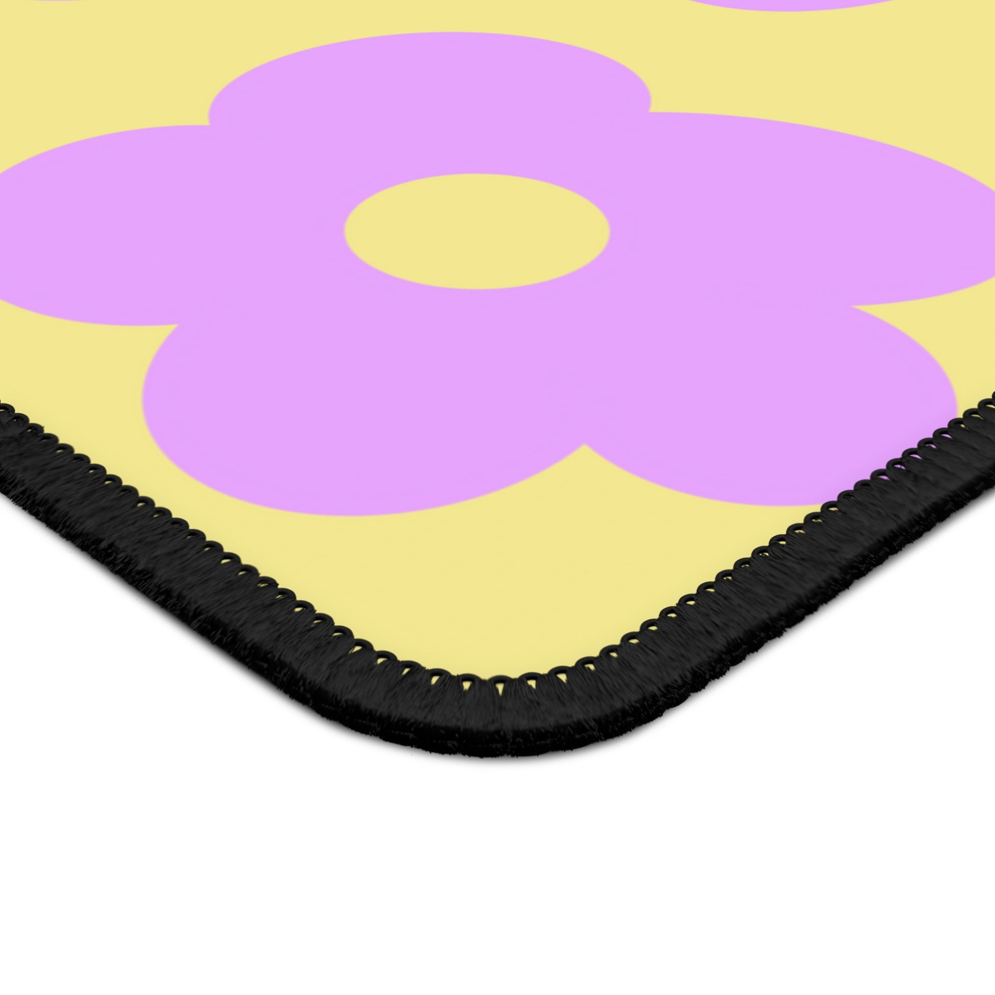 The corner of a gaming mouse pad with purple flowers on a yellow background.