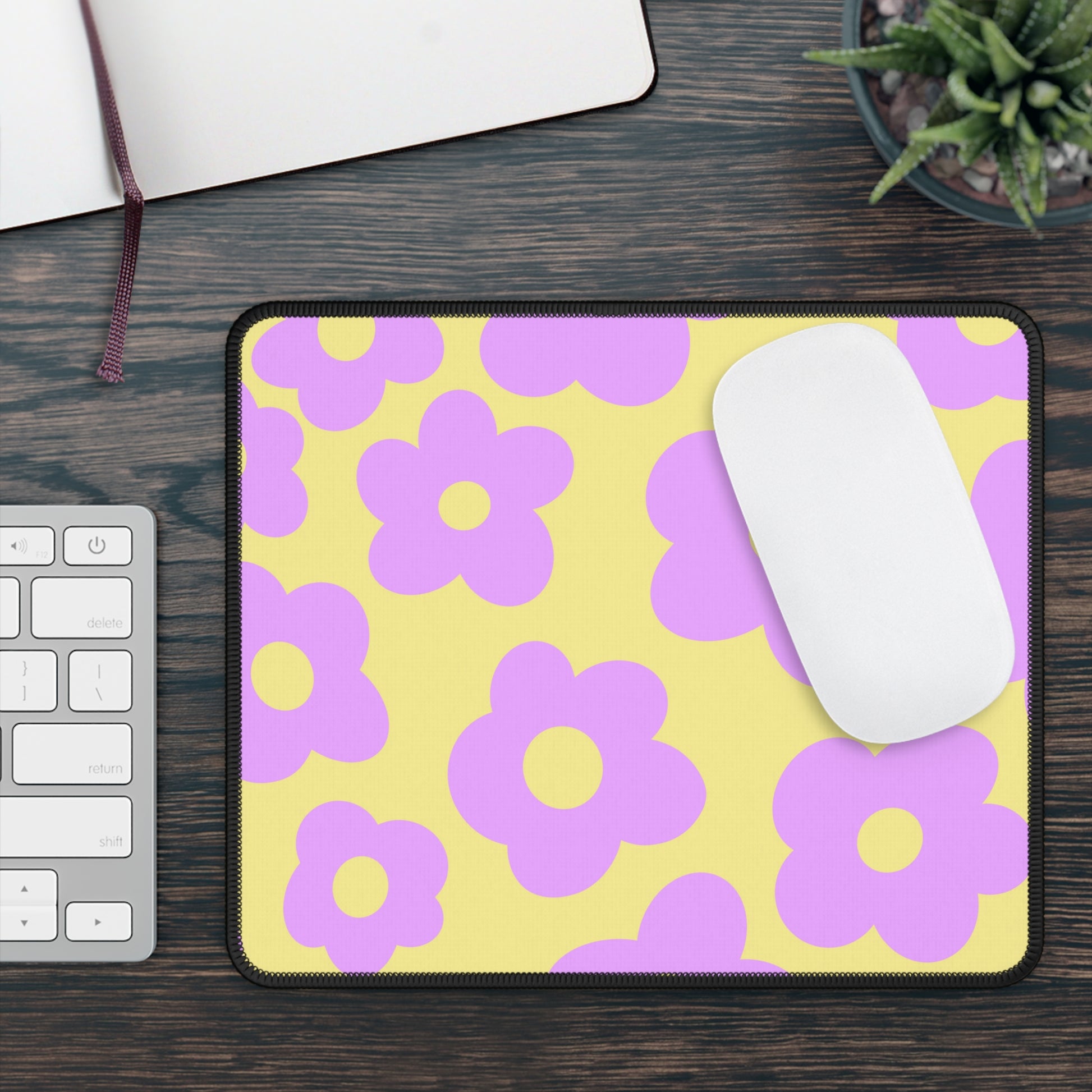 A gaming mouse pad with purple flowers on a yellow background. A mouse sits on top of it.