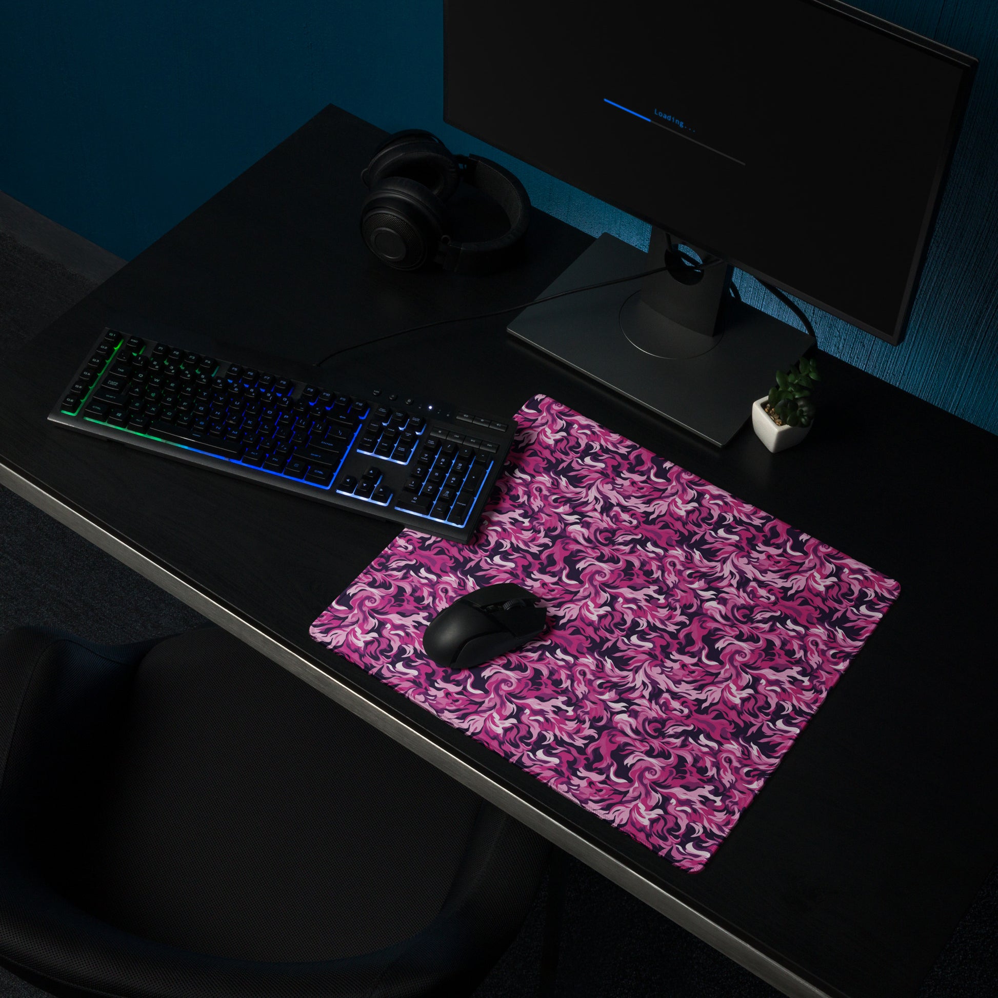 A 18" x 16" desk pad with a pink and magenta camo pattern sitting on a desk.