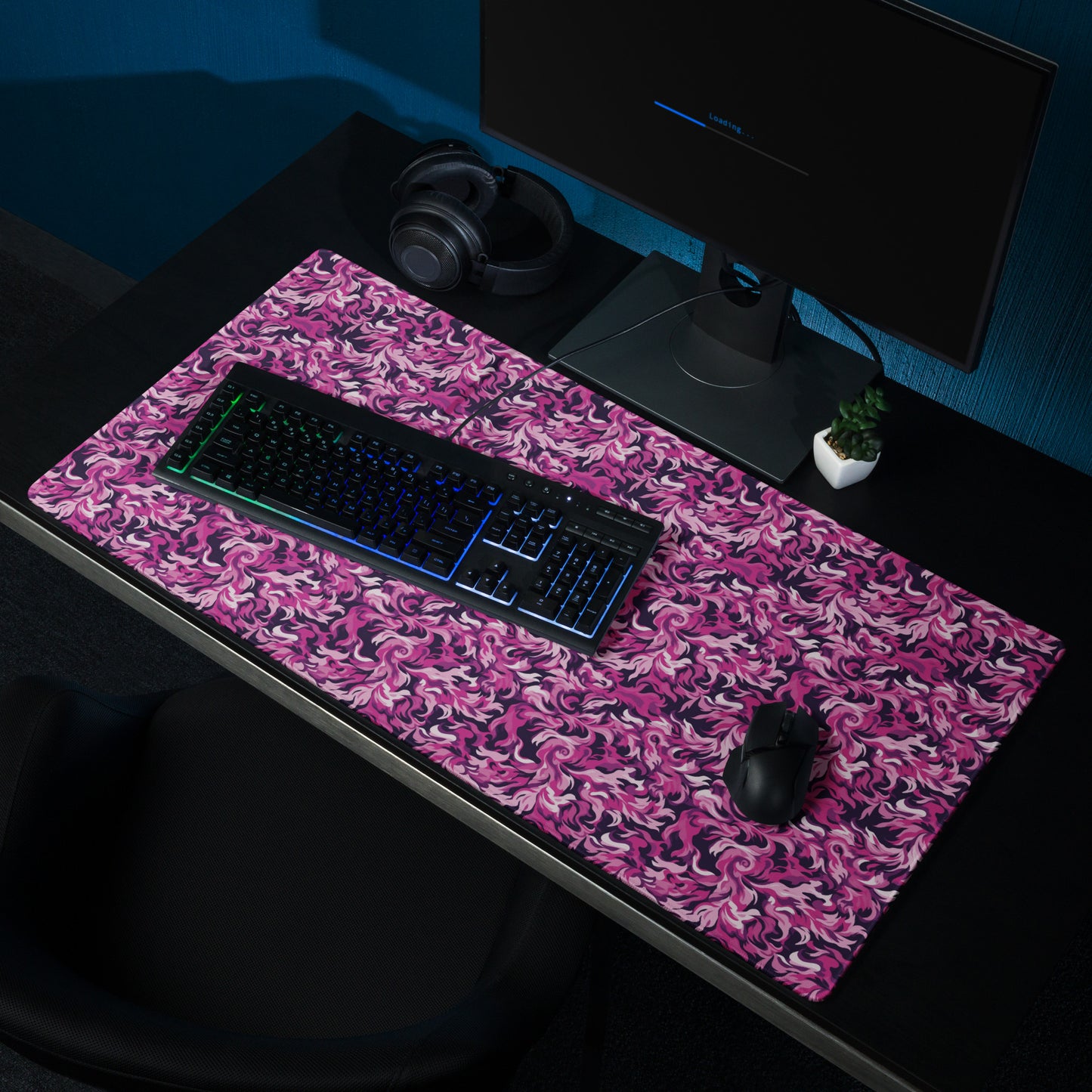 A 36" x 18" desk pad with a pink and magenta camo pattern sitting on a desk.