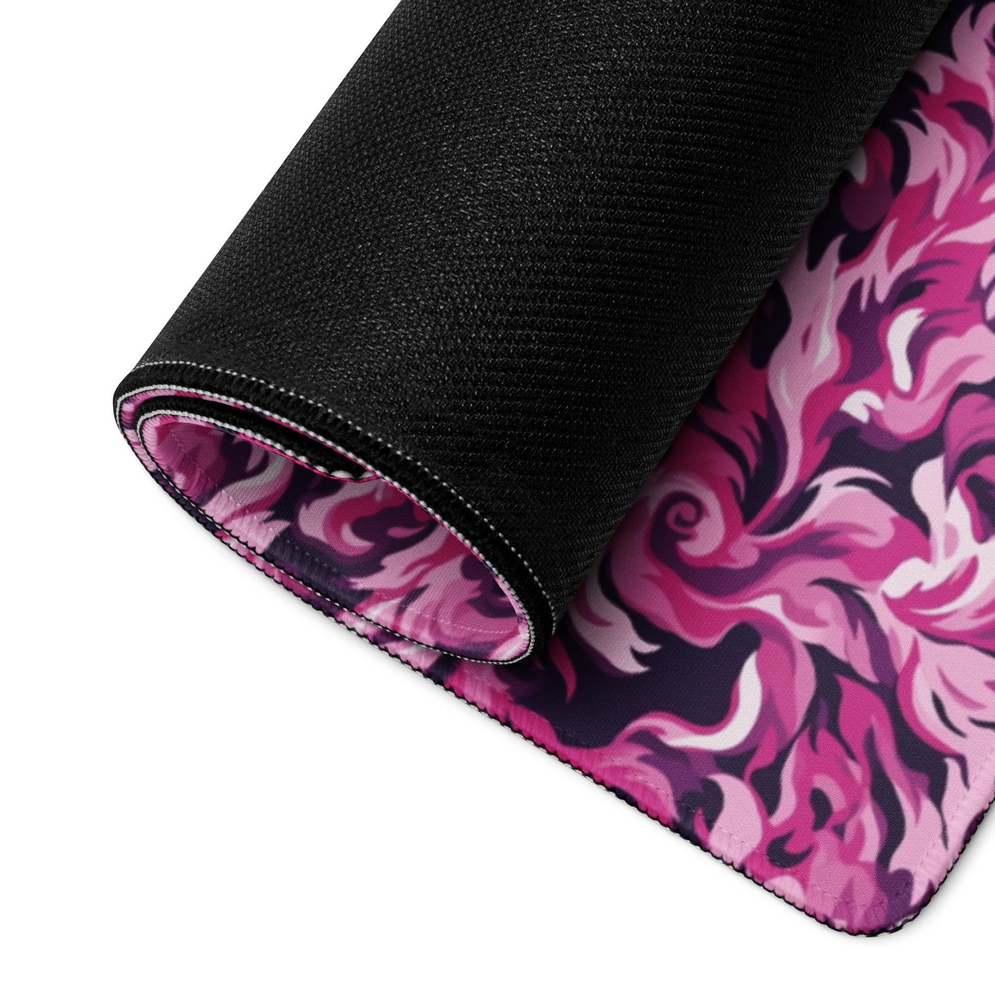 A 36" x 18" desk pad with a pink and magenta camo pattern rolled up.
