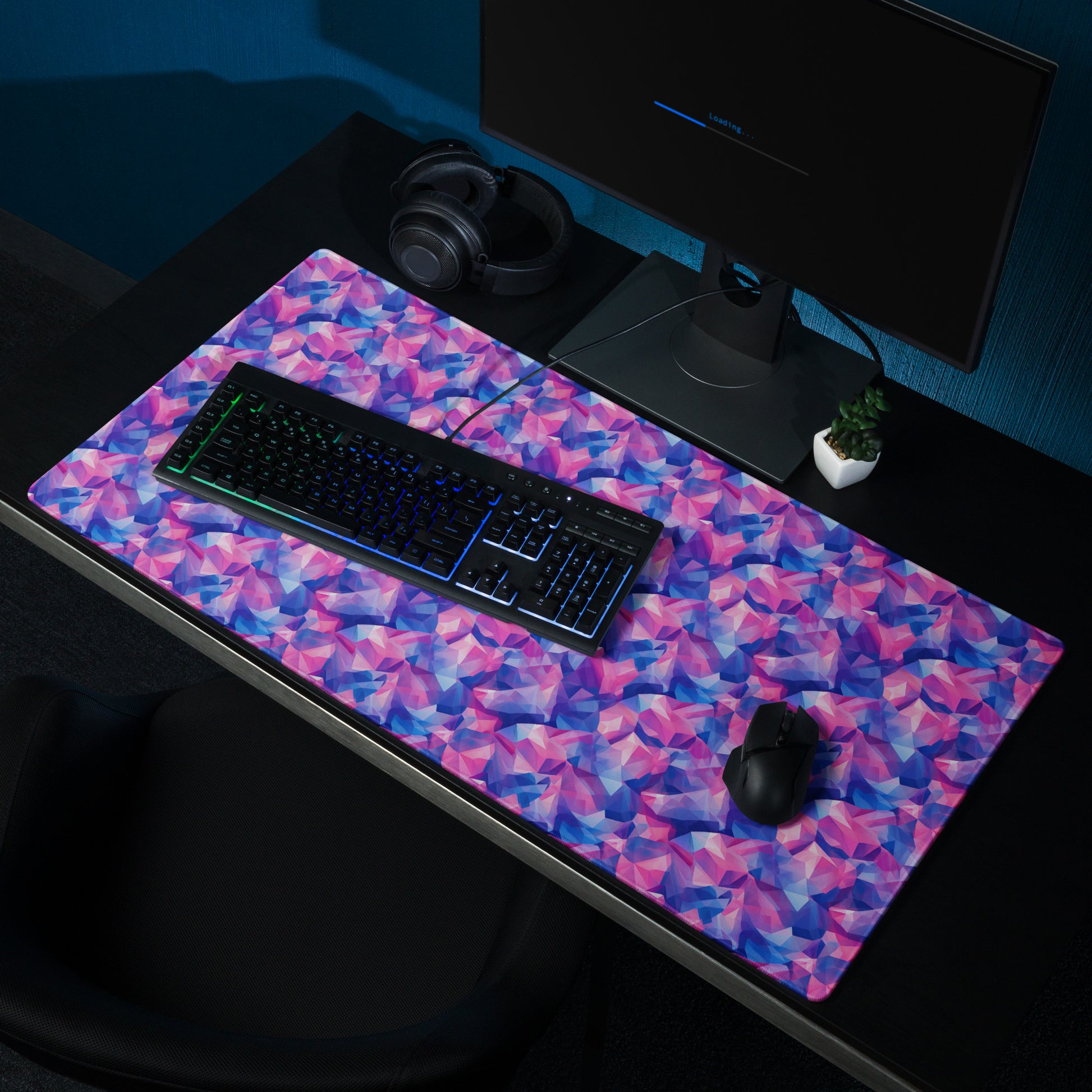 A 36" x 18" gaming desk pad with pink and blue crystals. It sits on a black desk with a monitor, keyboard, and mouse.