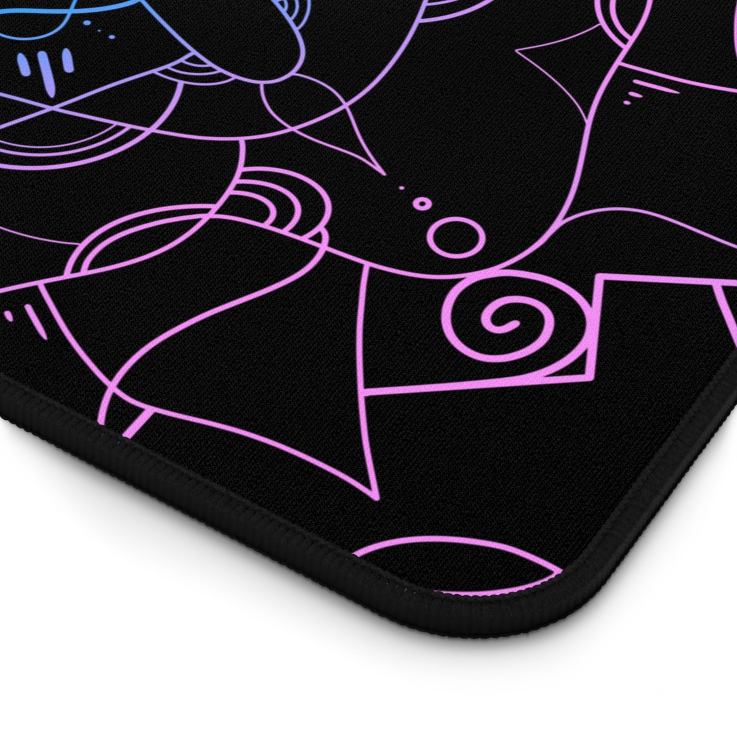 The corner of a 12" x 18" desk mat with a pink and blue mandala pattern on a black background.