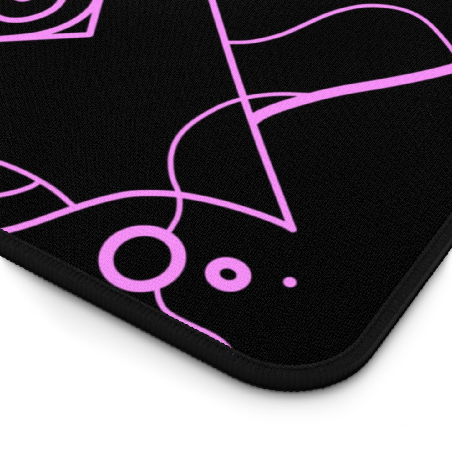 The corner of a 31" x 15.5" desk mat with a pink and blue mandala pattern on a black background.